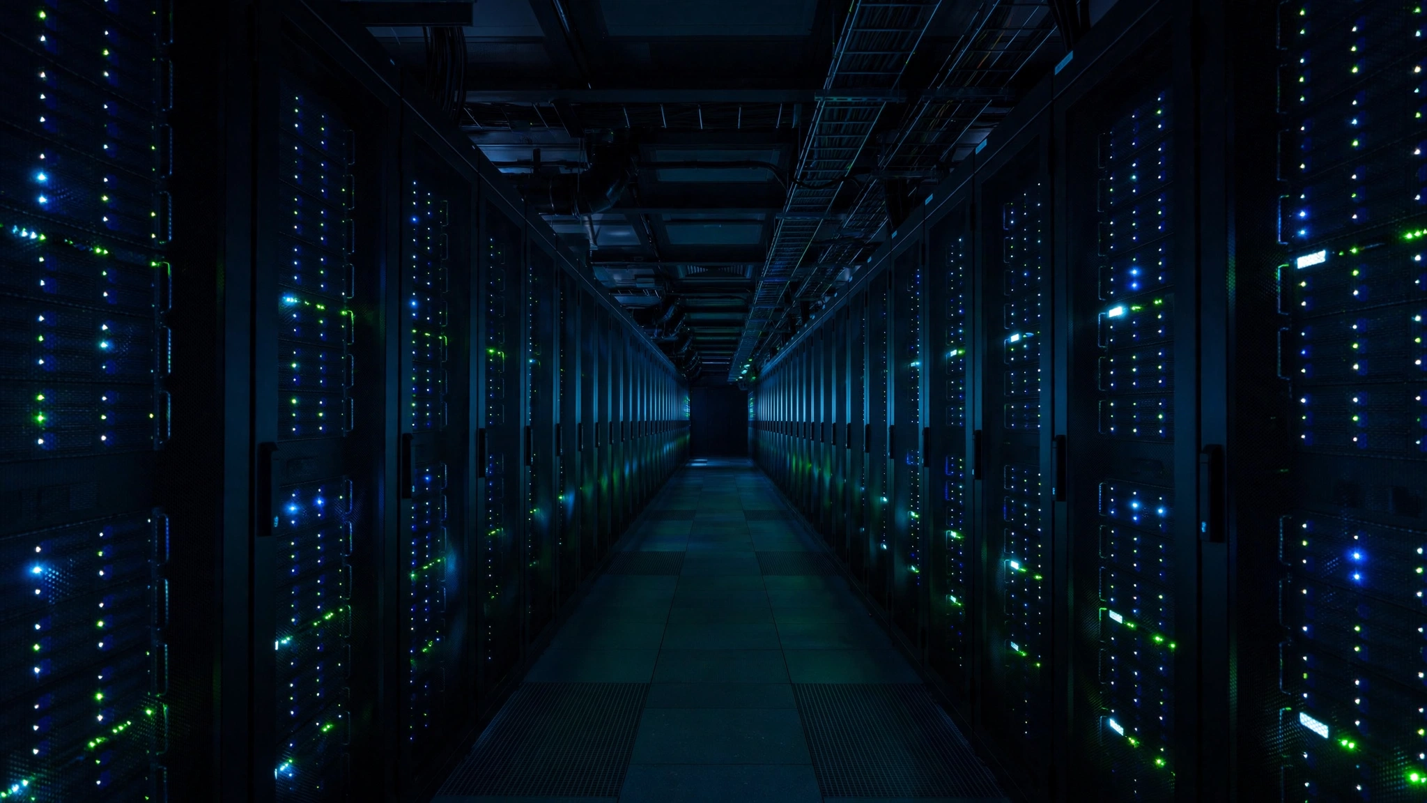 Rows of server racks with glowing blue and green indicator lights lining a dark data center corridor