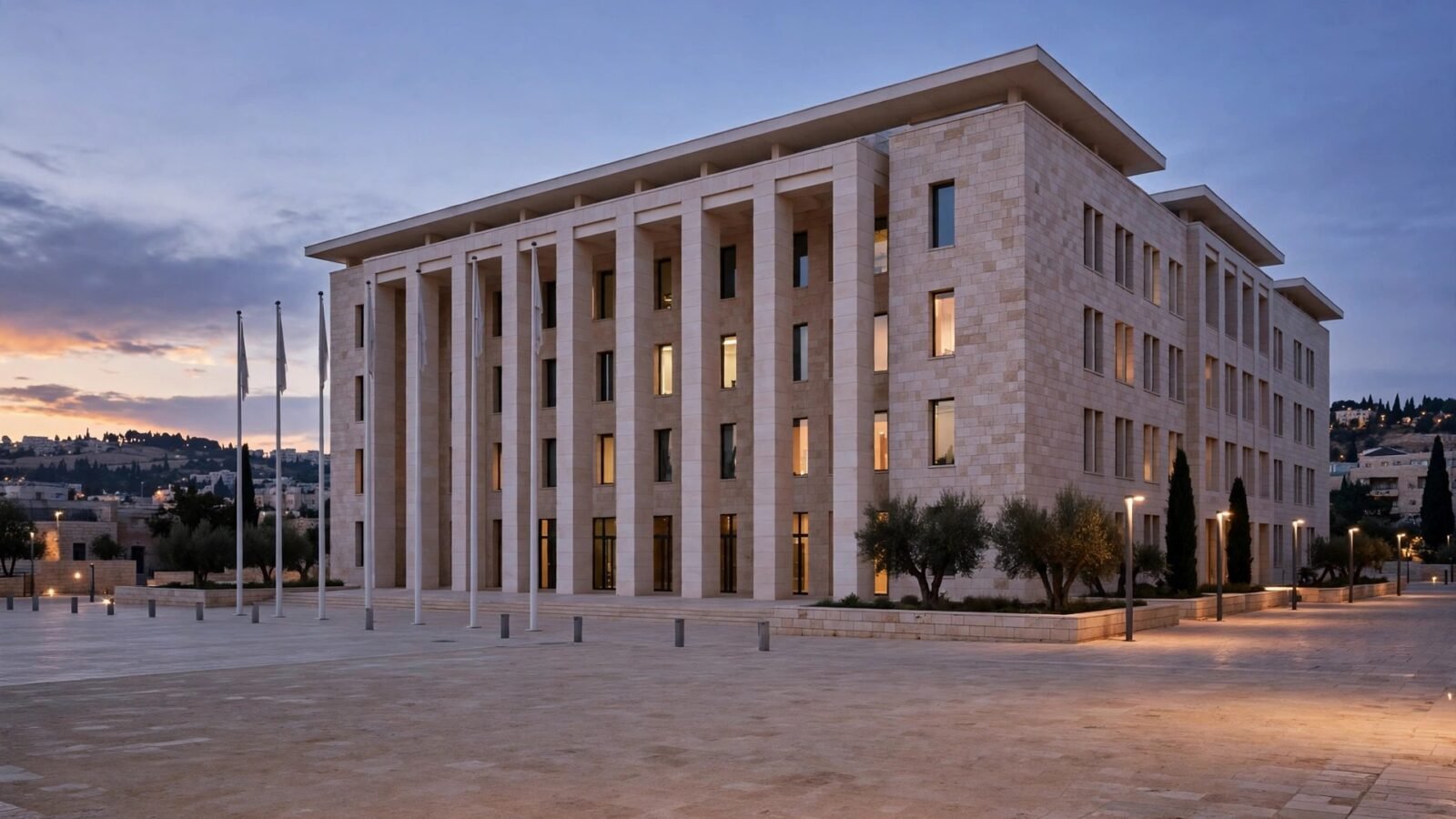 A large stone government building with tall columns and an empty paved plaza at dusk.