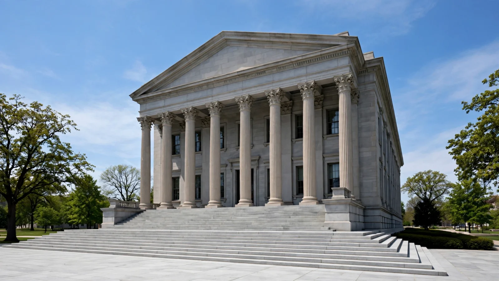 A stone courthouse building with tall columns and wide steps under a clear sky.