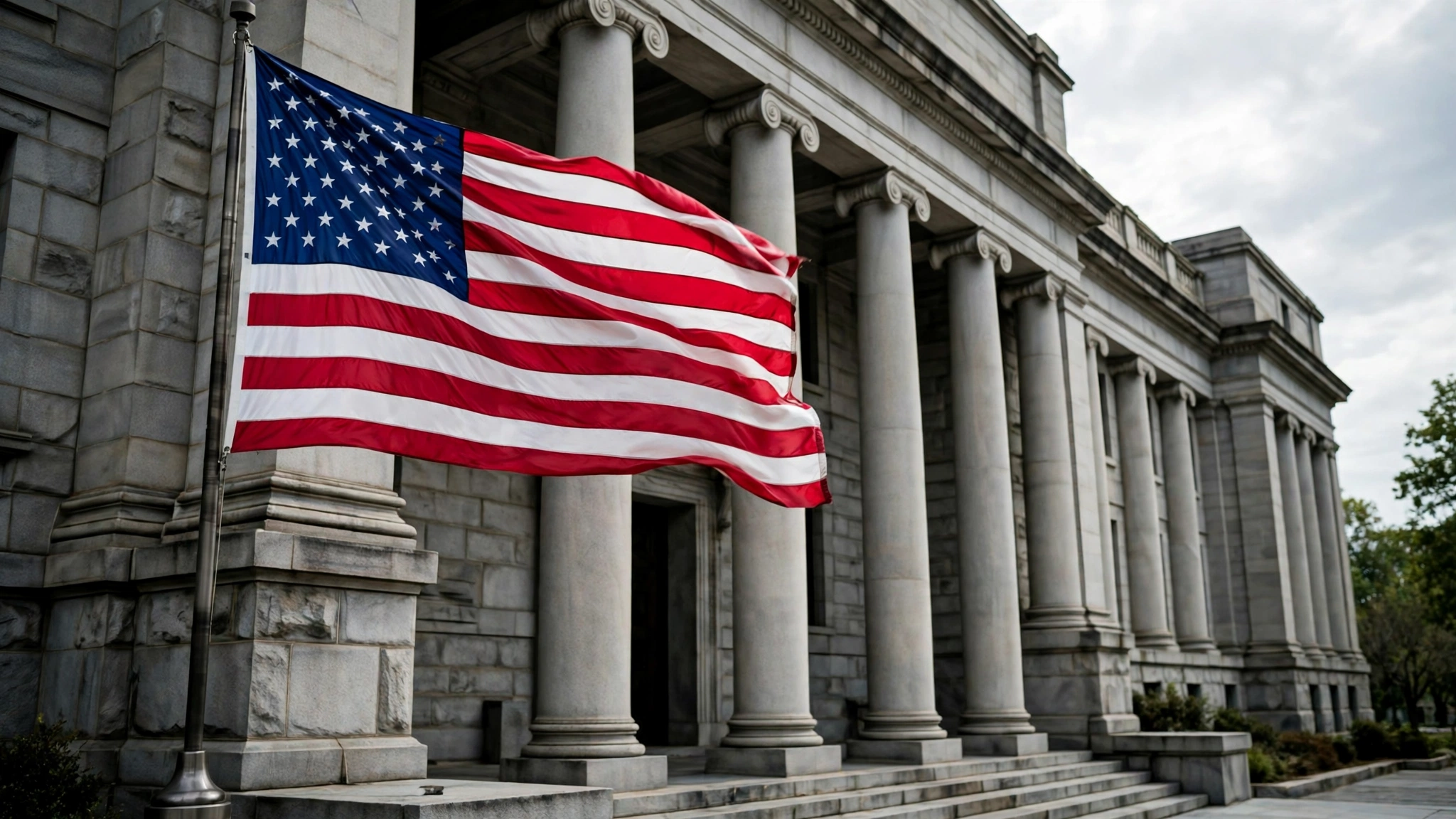 An American flag waving in front of a stone government building with tall columns.