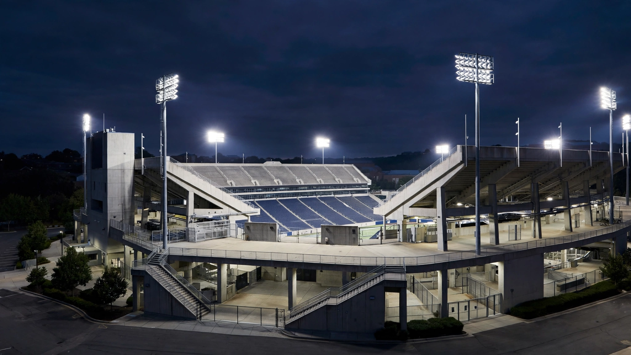 A college football stadium lit by floodlights at night with empty stands