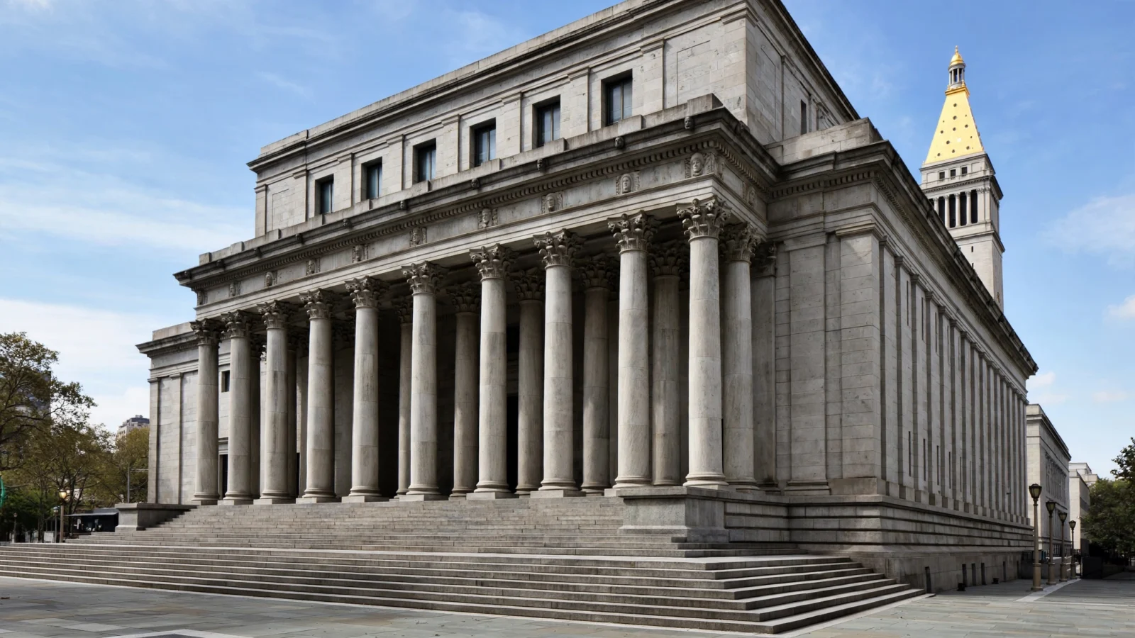 A stone federal courthouse building with tall columns and wide steps under a blue sky