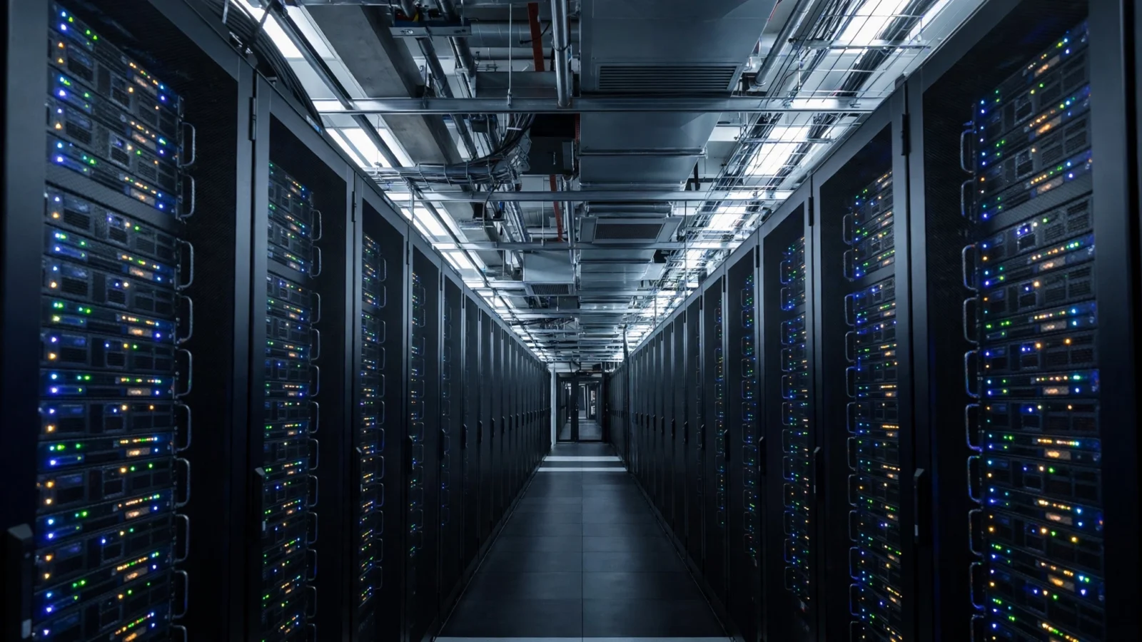 A long corridor in a data center with rows of black server racks and small blinking lights on both sides