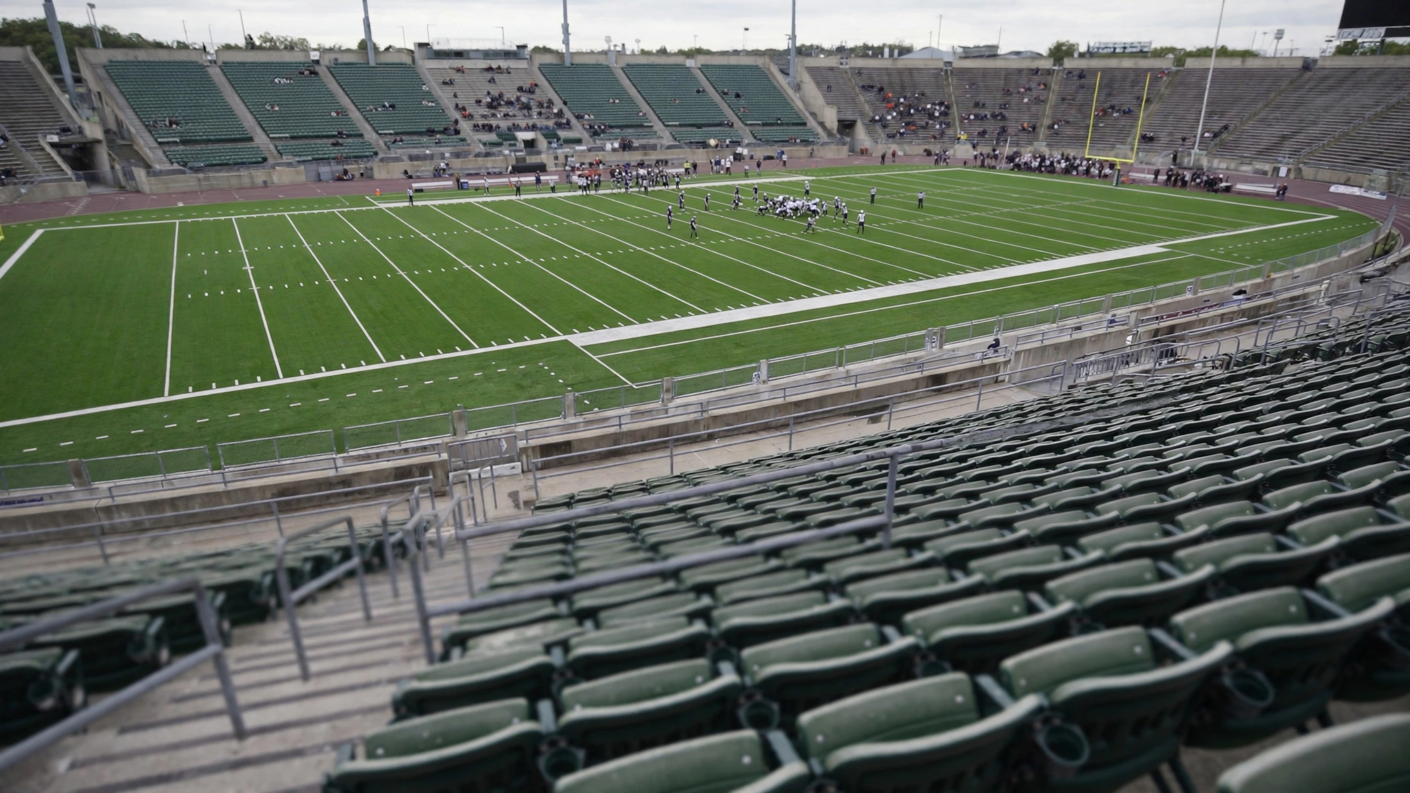 A football field viewed from stadium stands, with players small in the distance