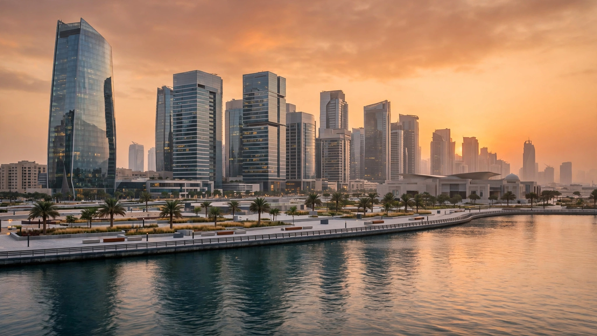 Modern skyscrapers and a waterfront promenade along calm water at sunset in Abu Dhabi