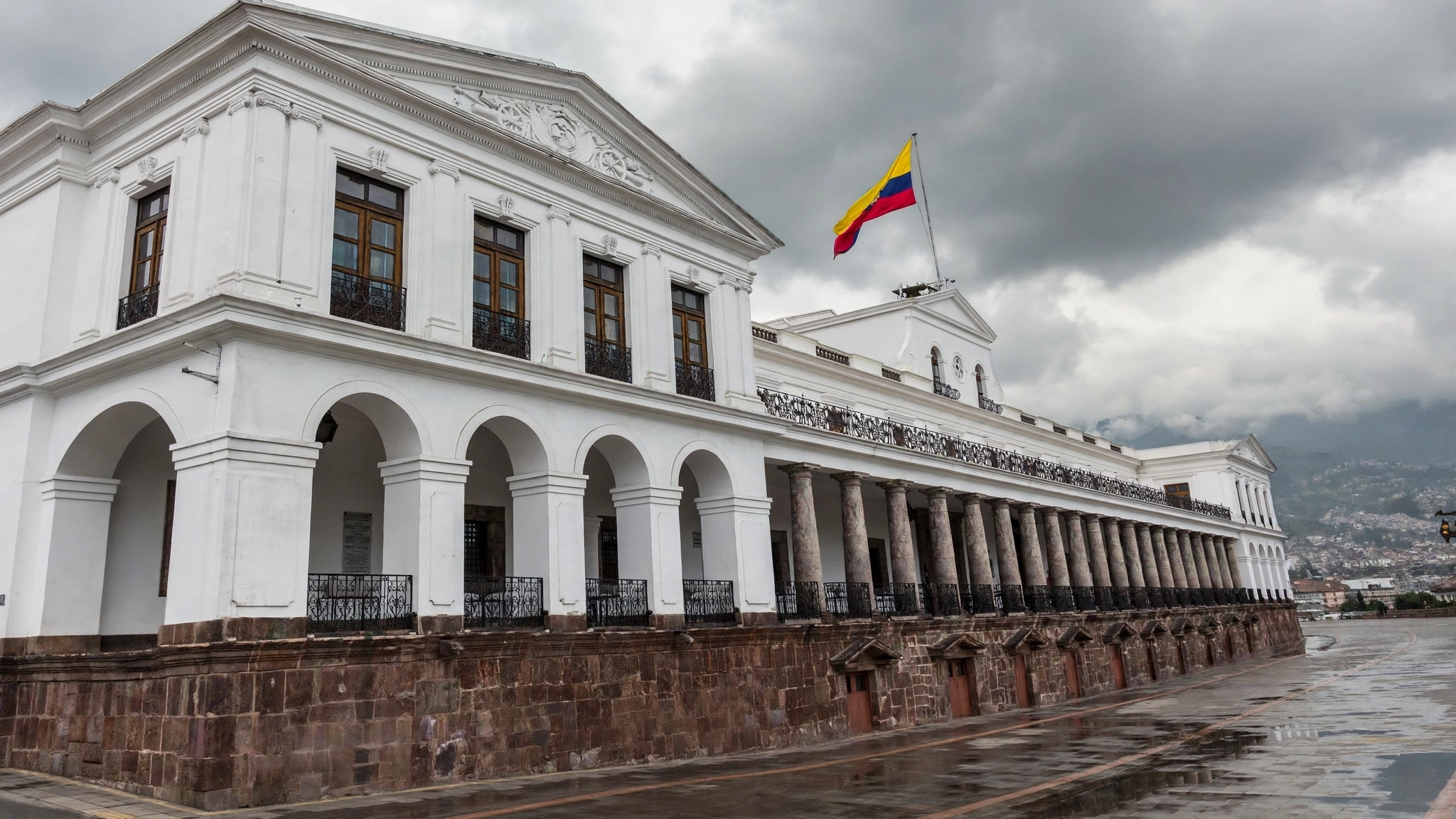 A white government building with columns and an Ecuadorian flag flying above it