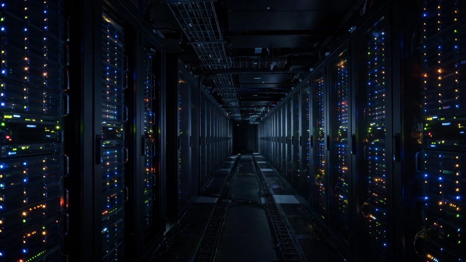 Rows of server racks with blinking indicator lights inside a dark data center corridor.