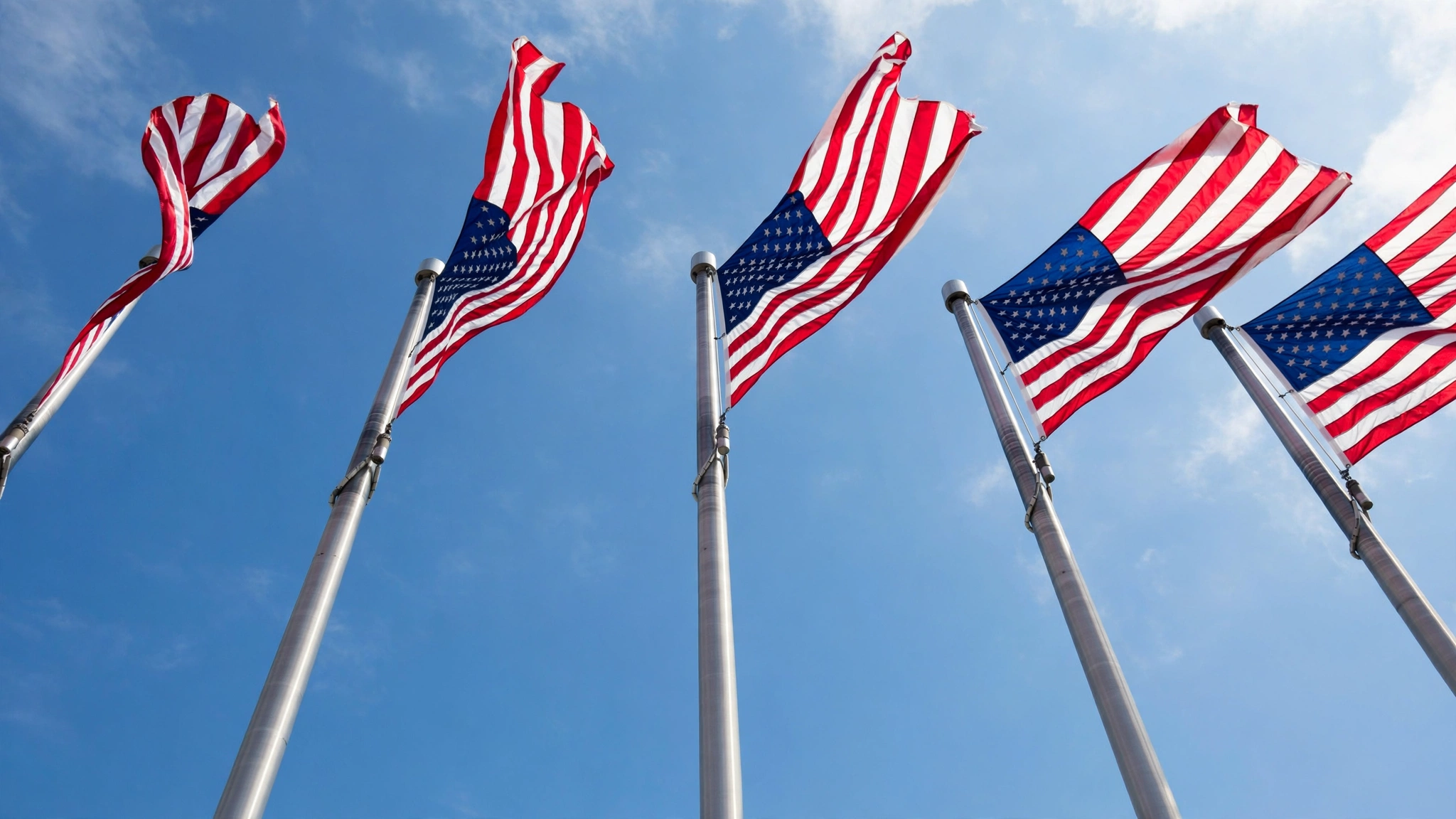 American flags on tall flagpoles waving against a blue sky