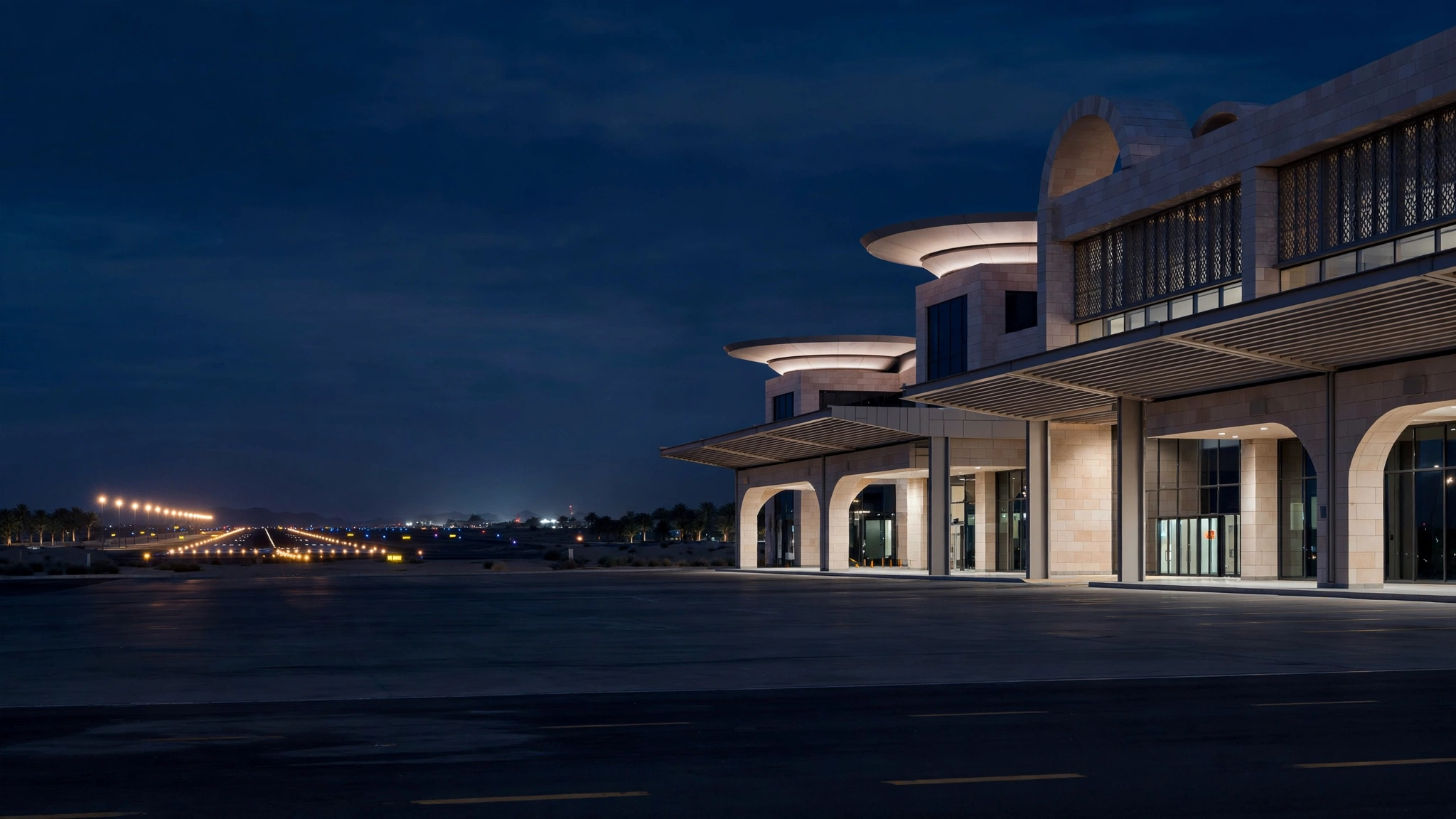 The exterior of a Middle Eastern airport terminal building lit up at night with runway lights in the distance.