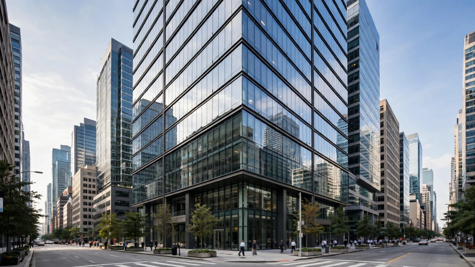 A modern glass office building on a city street with pedestrians on the sidewalk