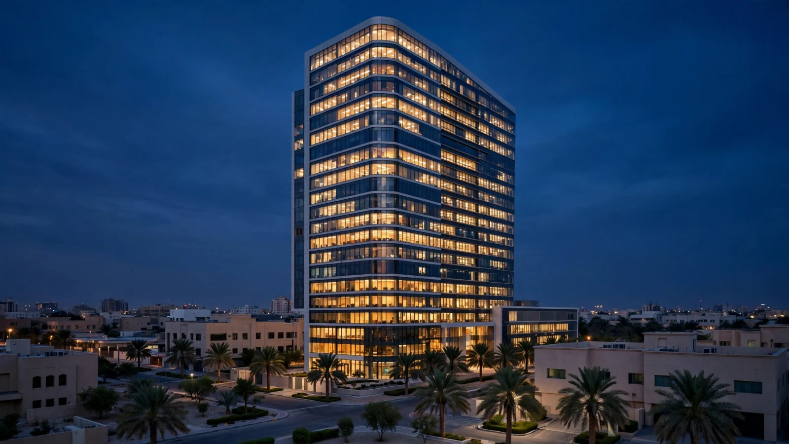 A modern illuminated office tower at night in a Middle Eastern city, surrounded by palm trees and low-rise buildings