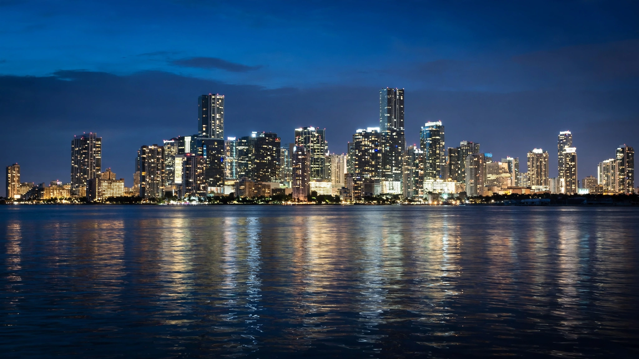 The Miami skyline lit up at night, seen across the water