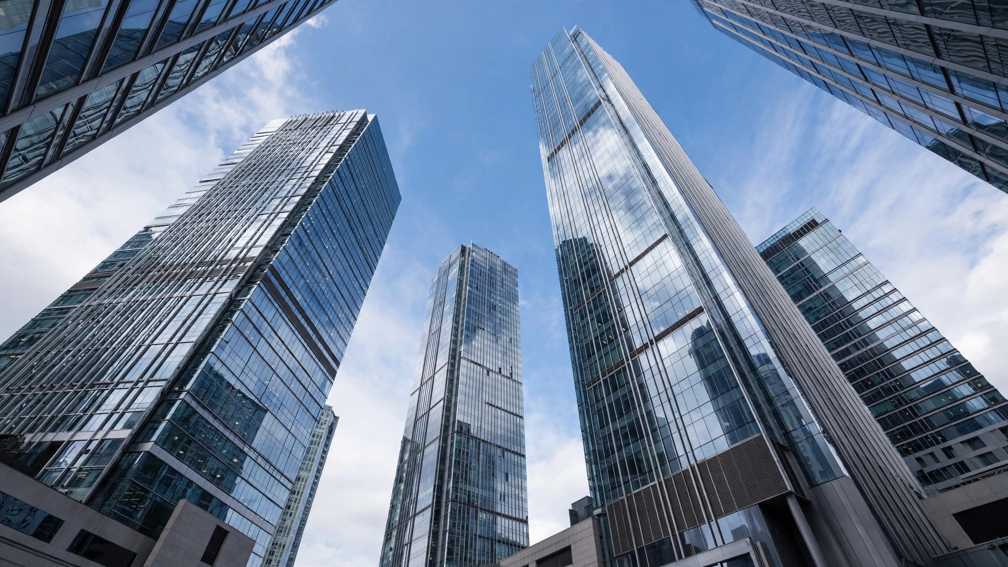 Tall glass corporate skyscrapers seen from below against a blue sky in a financial district