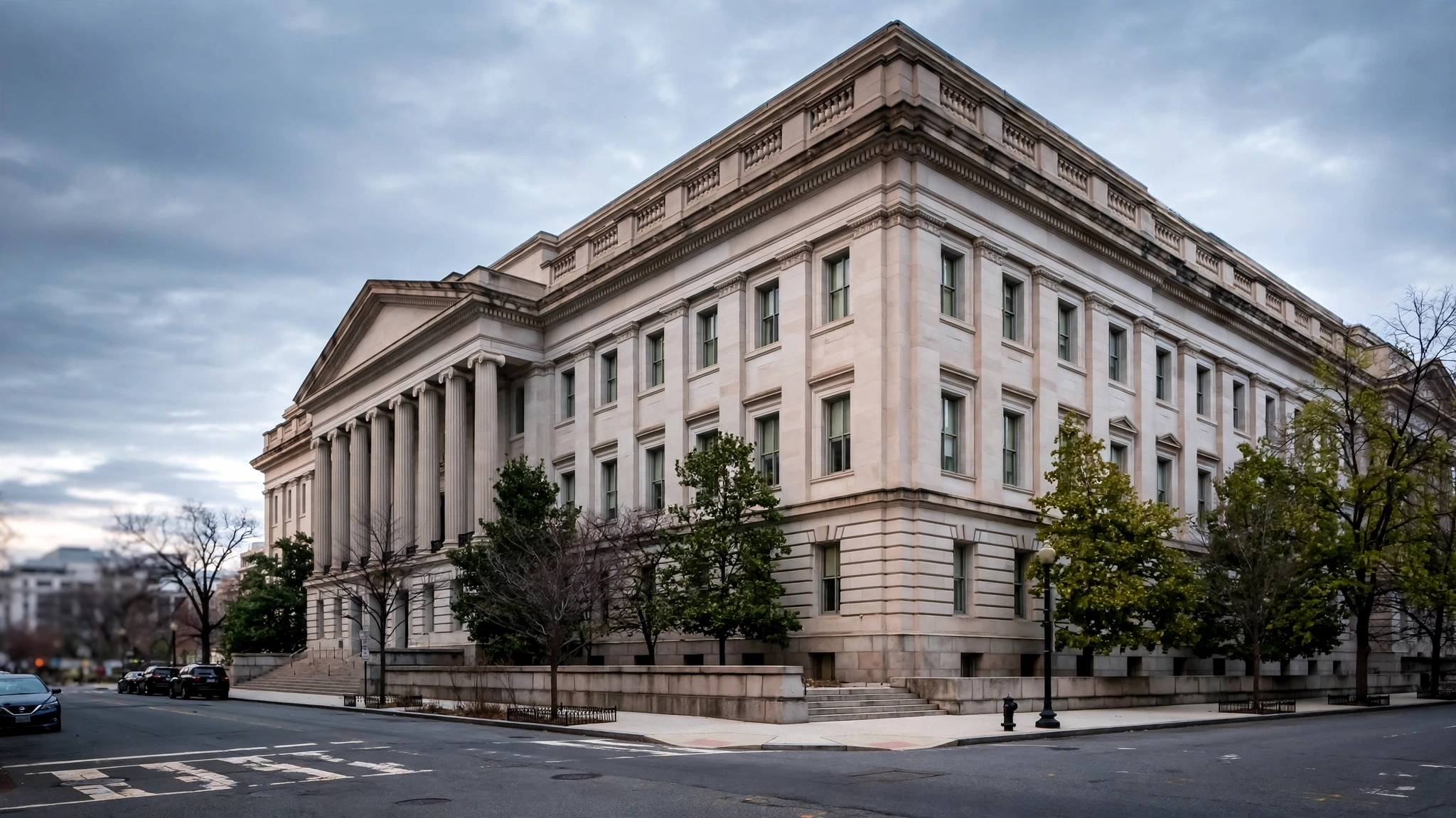 A large stone government office building with columns on a street corner in Washington