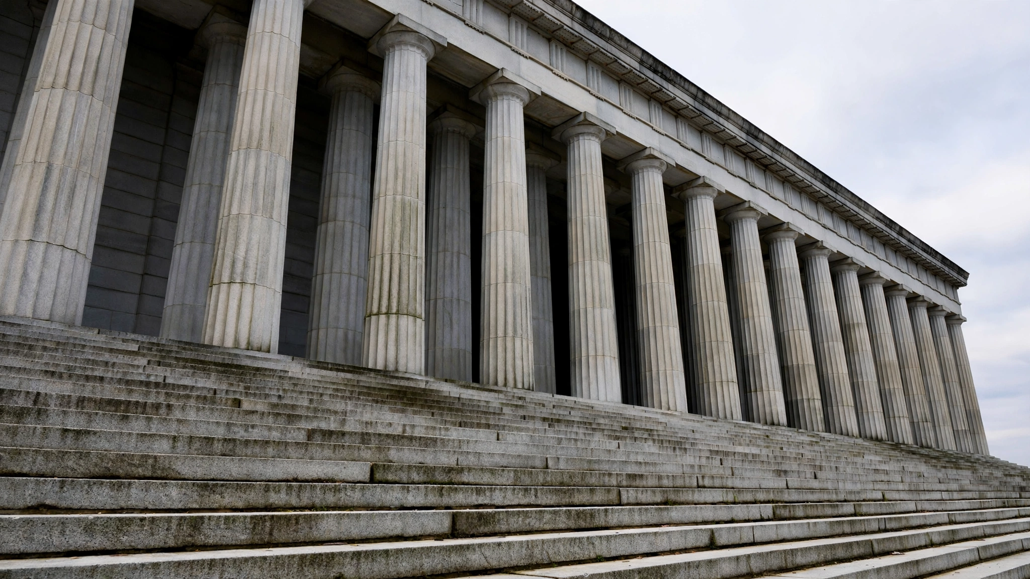 Tall stone columns and steps of a government building in Washington against a pale sky