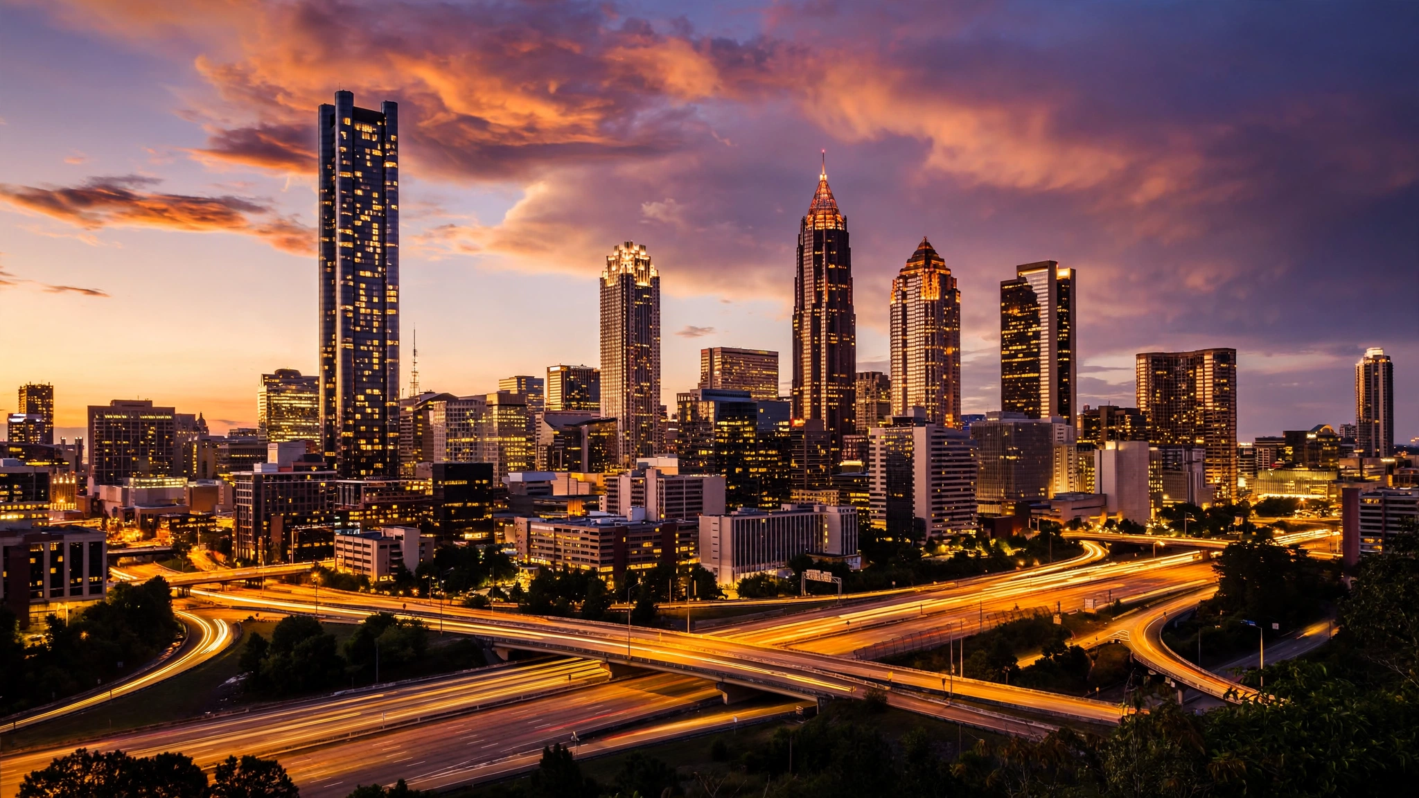 The Atlanta skyline at dusk with lit skyscrapers and light trails on the freeway below