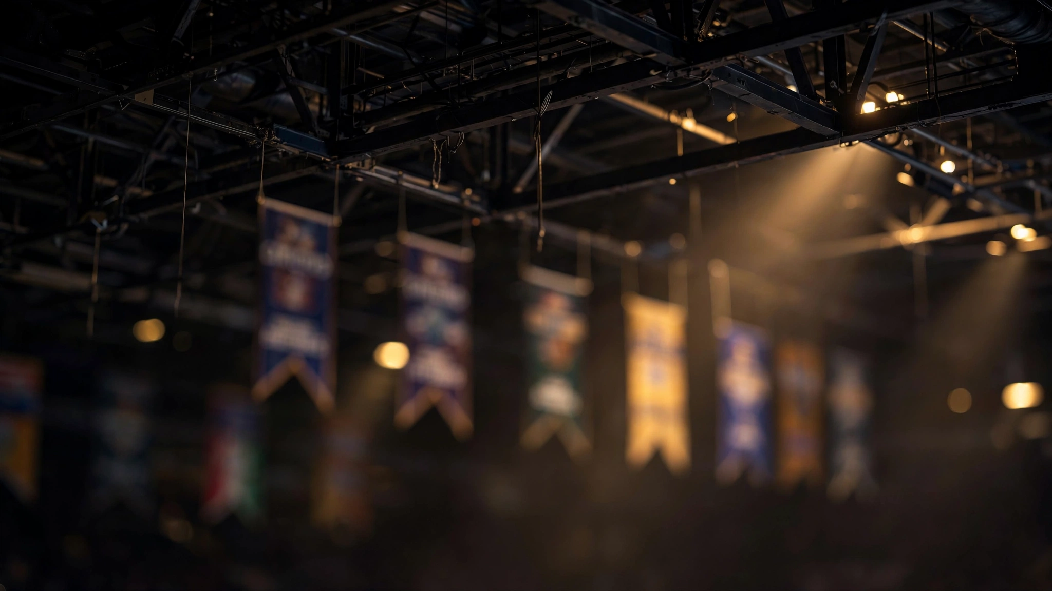 Championship banners hanging blurred in the dark rafters of a sports arena