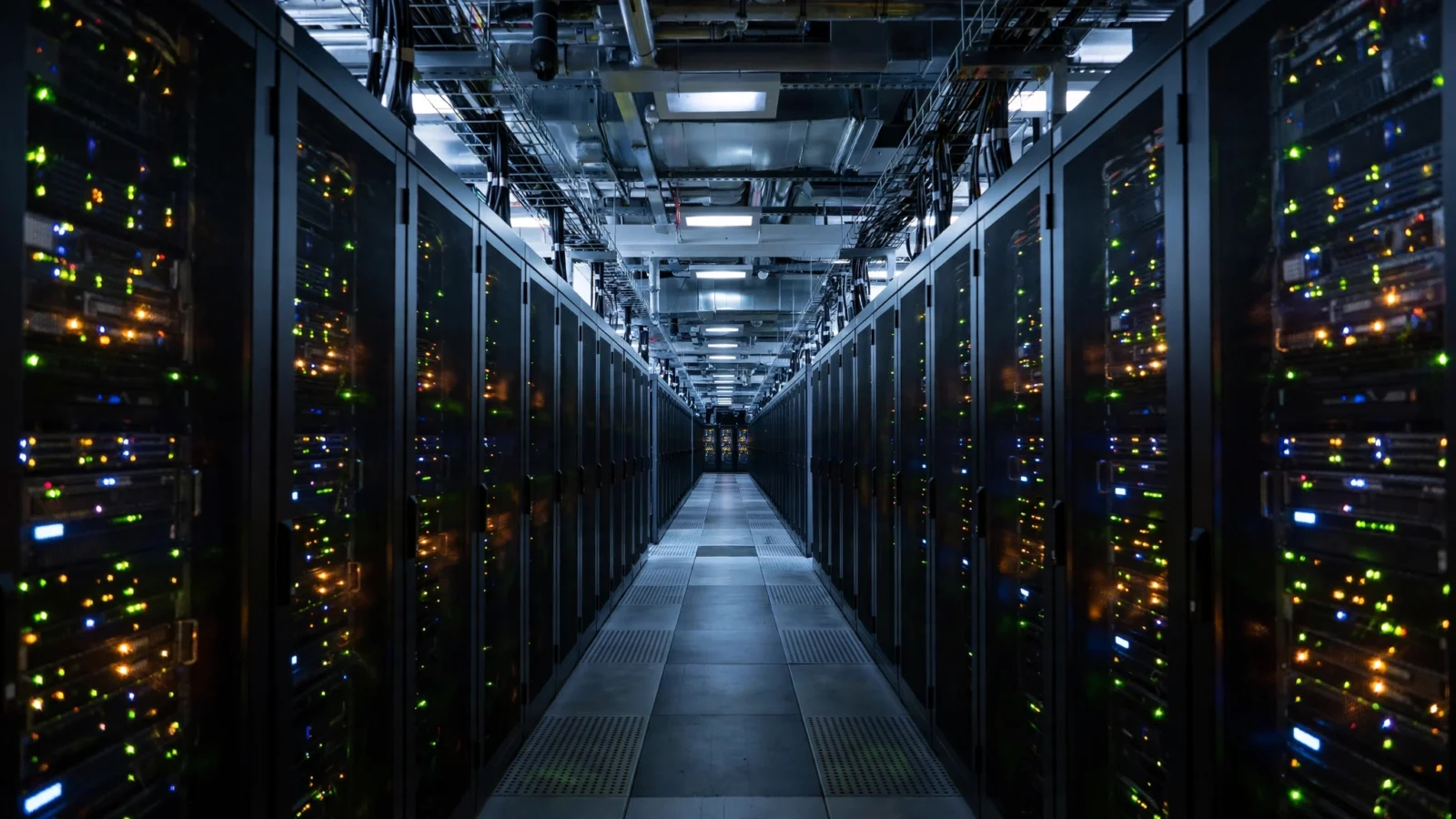A corridor between rows of server racks with small lights in a data center