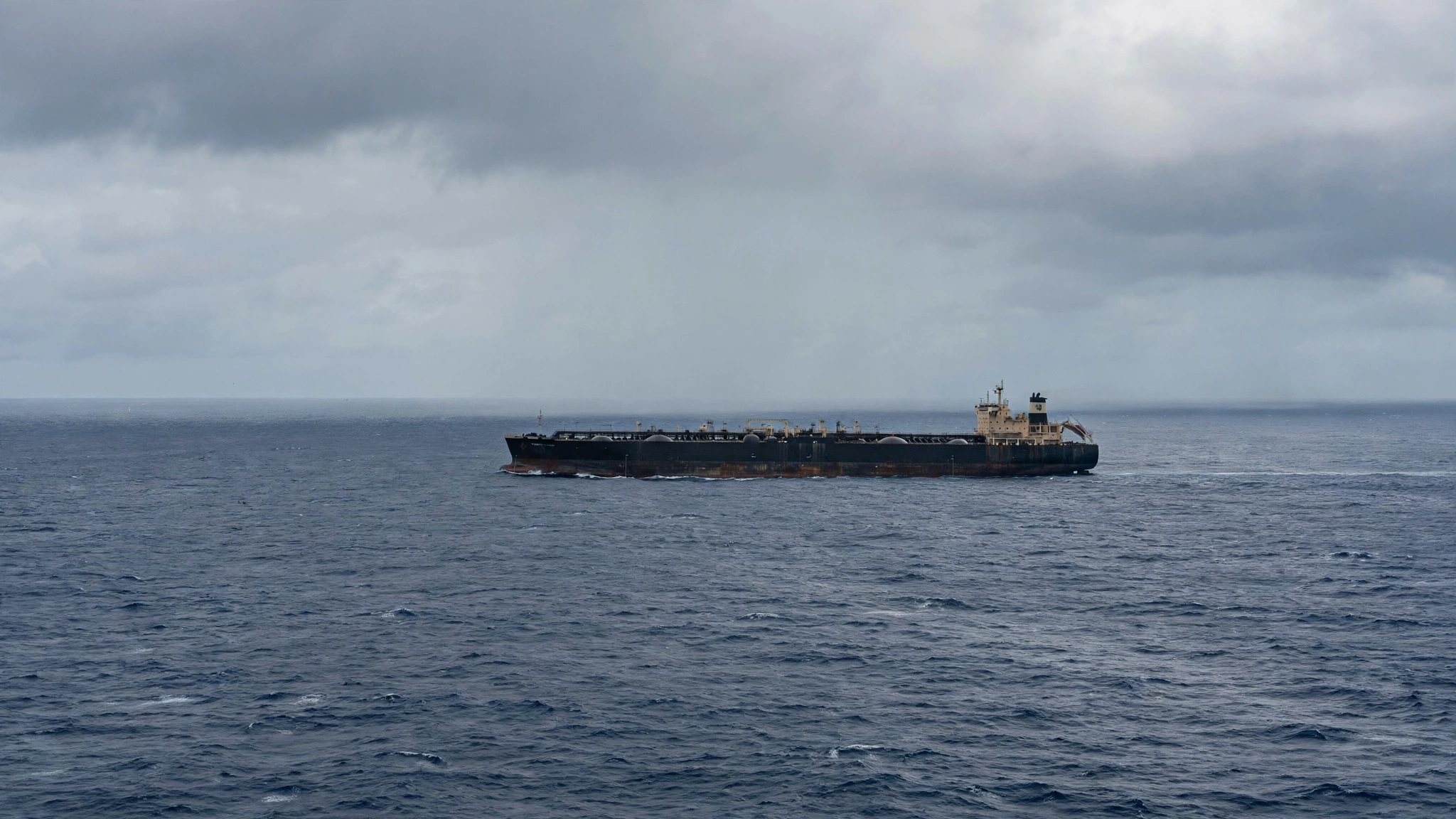 A large crude oil tanker sailing on the open ocean under an overcast sky