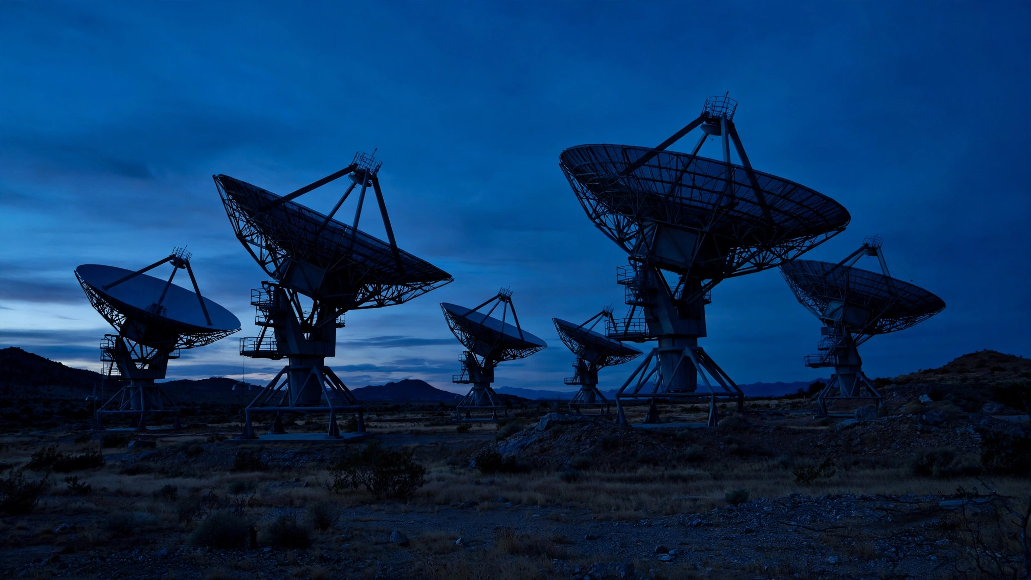 Large satellite communication dishes silhouetted against a twilight sky
