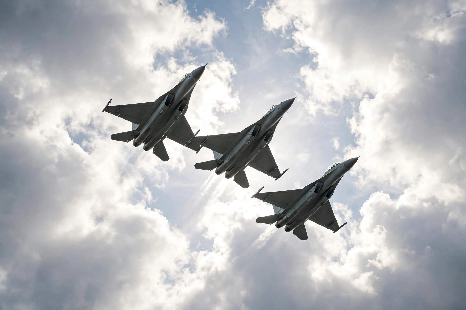 Three military fighter jets flying in formation through cloudy skies