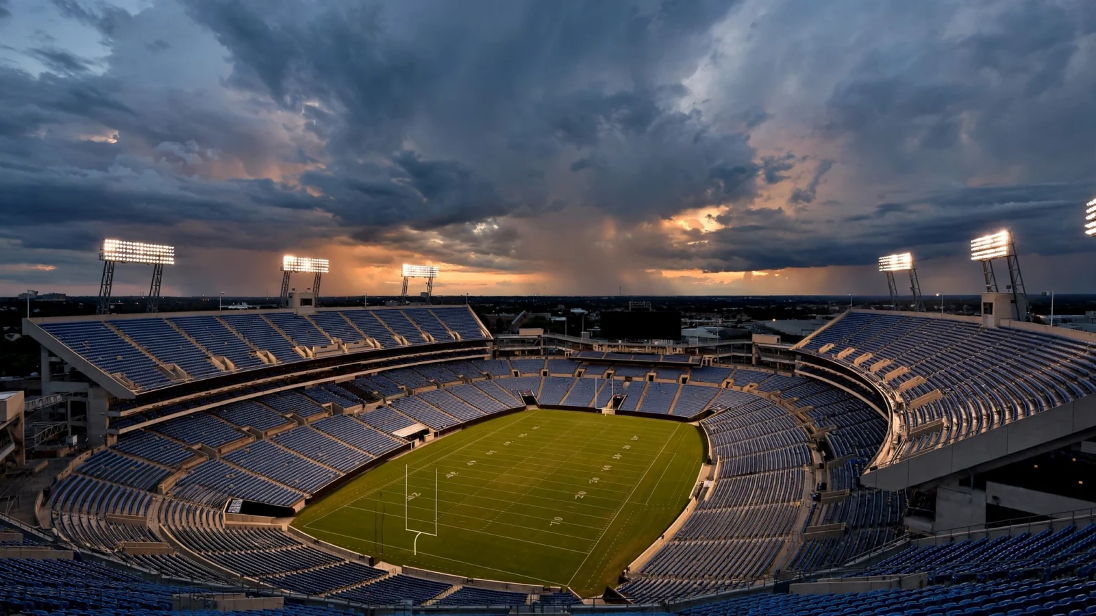 An empty American football stadium under bright floodlights at dusk