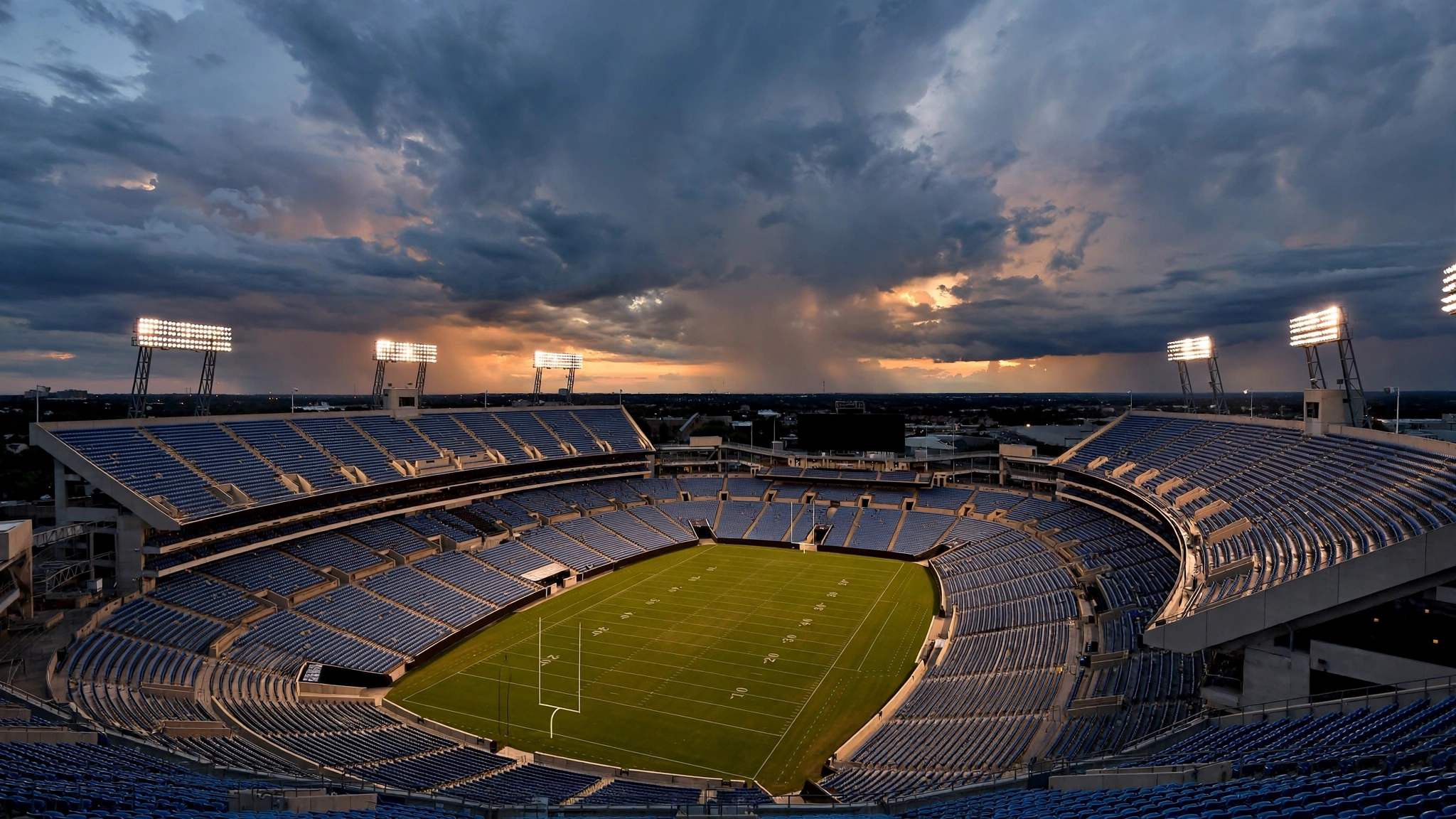 An empty American football stadium under bright floodlights at dusk