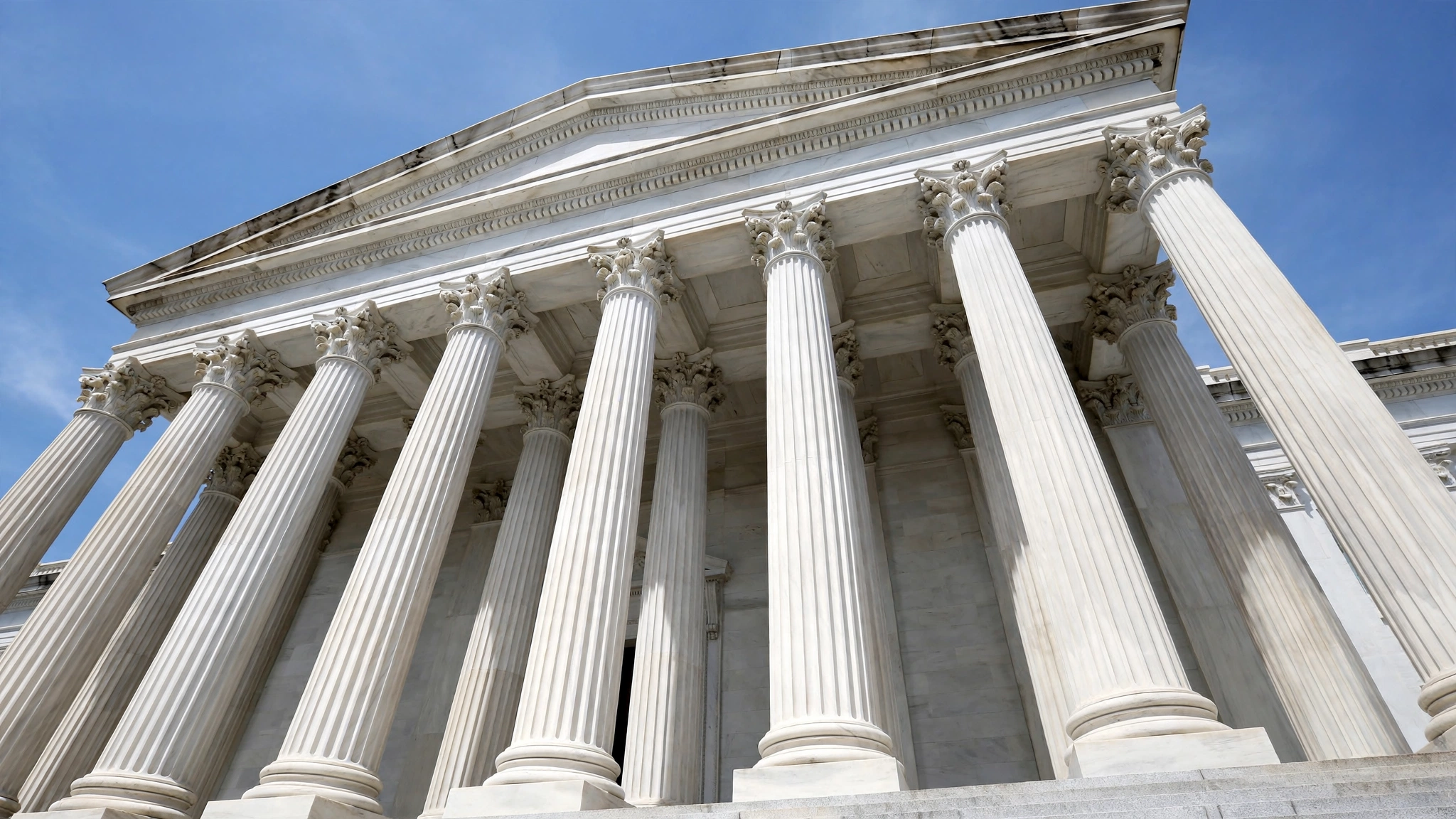 White marble columns of a neoclassical government building against a blue sky