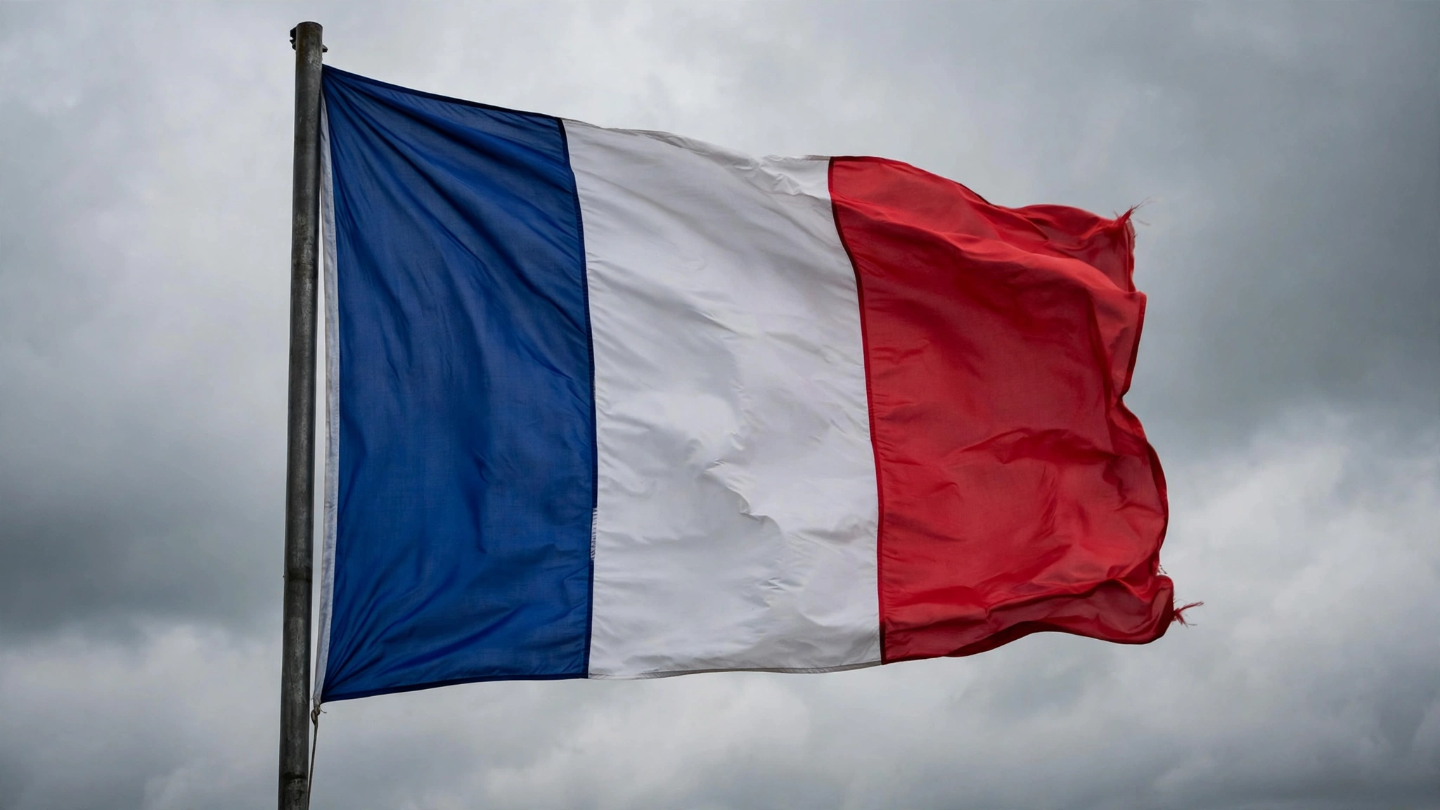The French tricolor flag flying against an overcast sky