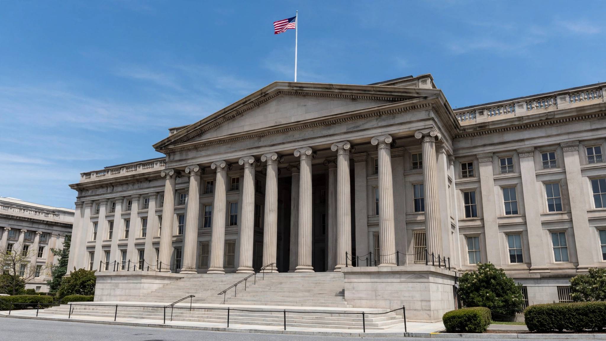 The columned stone facade of the U.S. Treasury Department building in Washington, D.C., under a clear sky.
