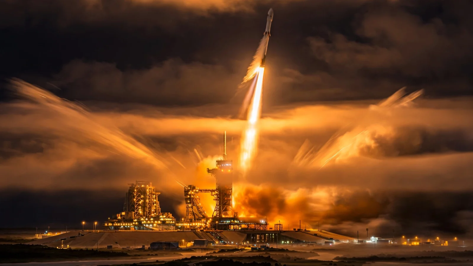 A rocket launching at night with a bright exhaust plume over the launch pad