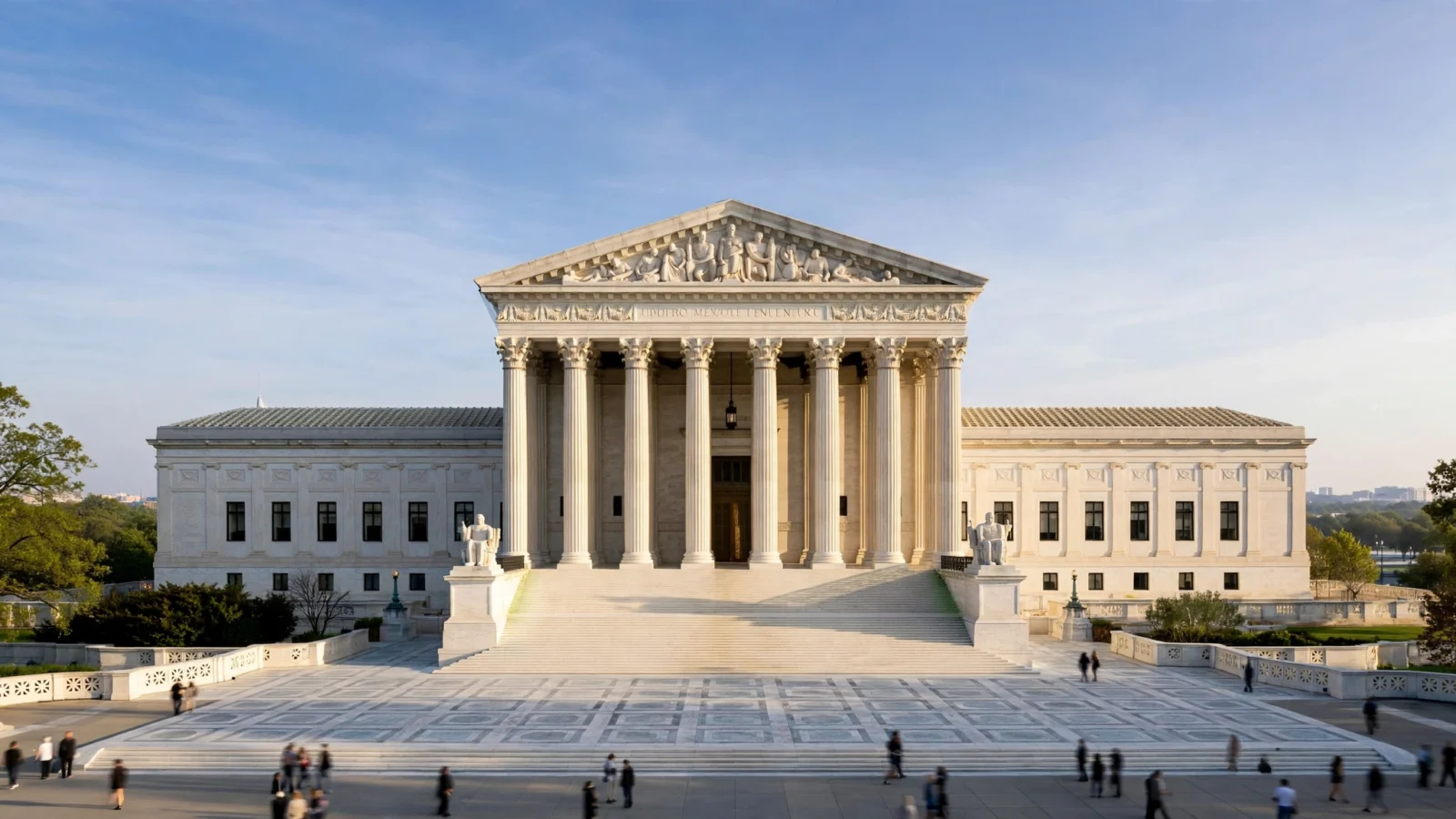 Front view of the U.S. Supreme Court building in Washington, D.C., with marble columns, wide steps and a plaza in morning light.