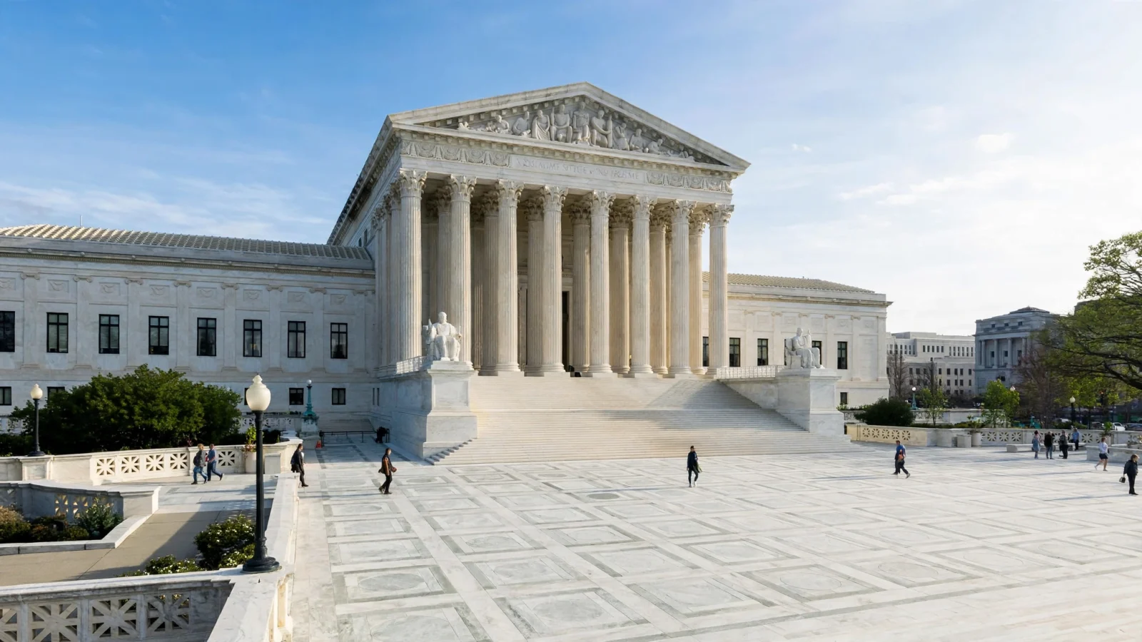 The marble facade and columns of the U.S. Supreme Court building in Washington, D.C., with visitors on the plaza