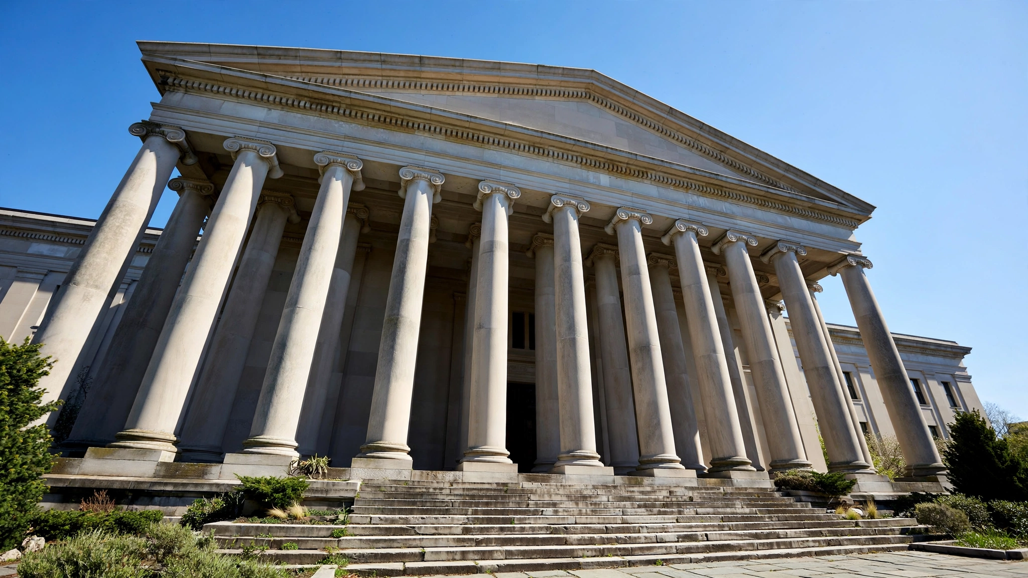 The columned facade of a neoclassical federal government building against a blue sky