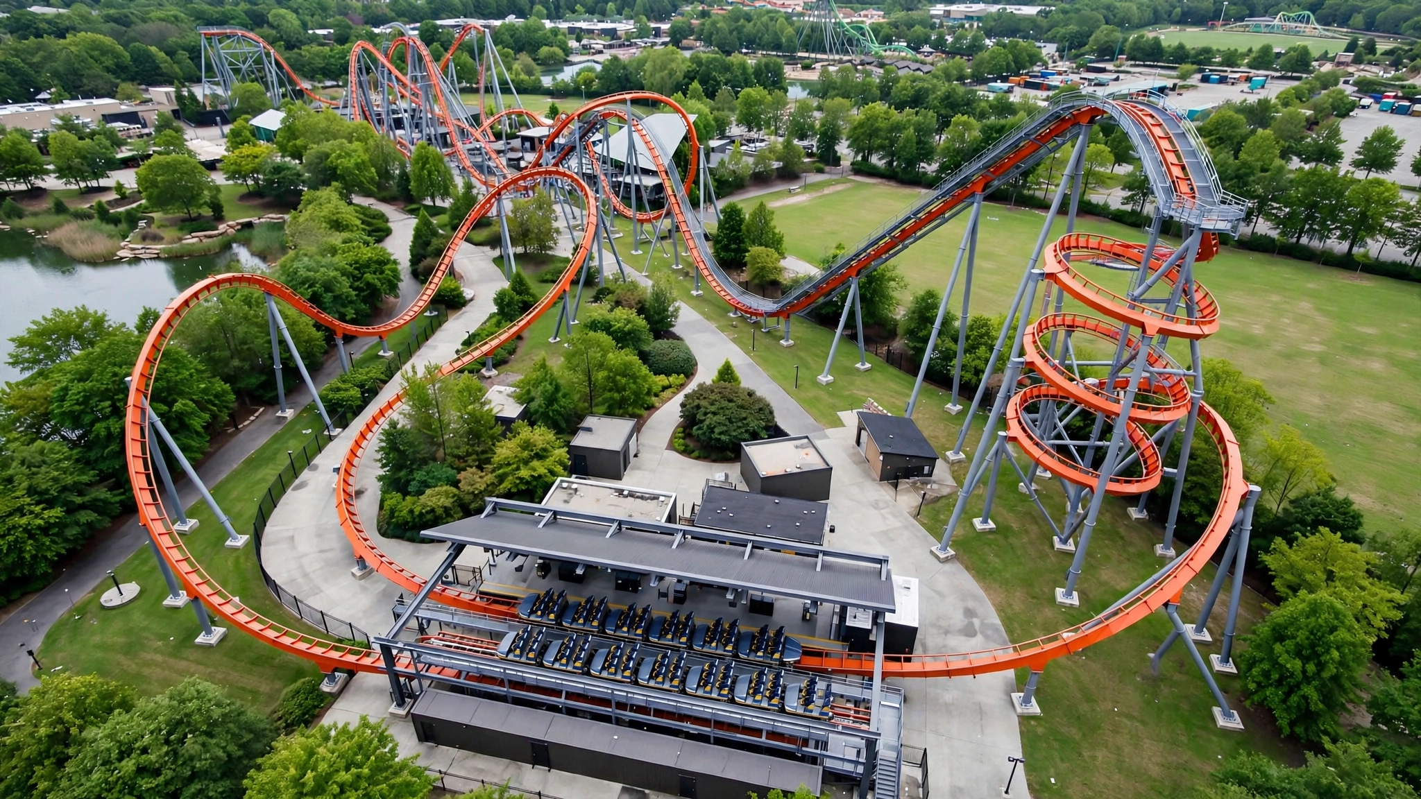 High-angle view of a steel roller coaster with an orange track winding through a theme park