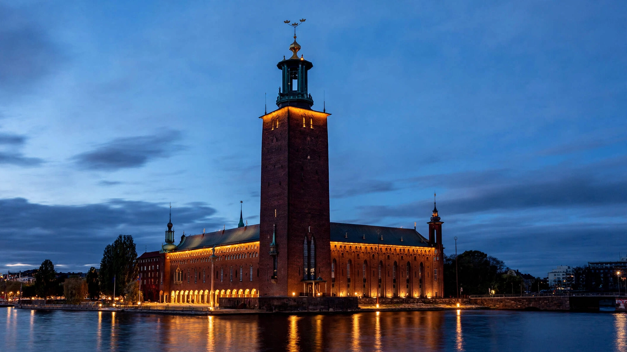 Stockholm City Hall lit up at dusk, reflected in the water.
