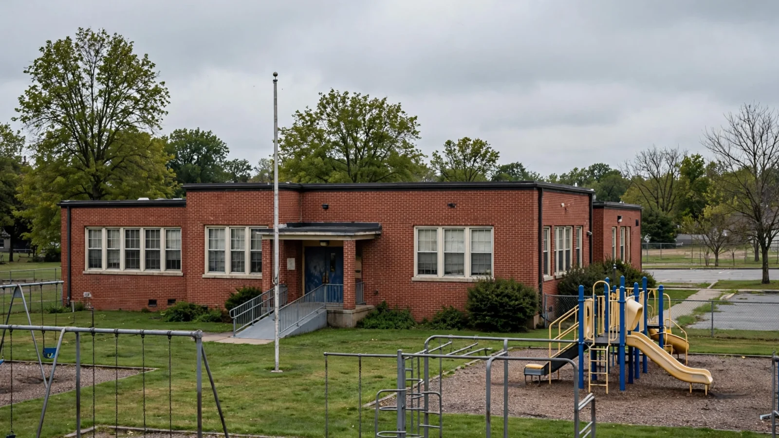 Brick elementary school building with empty playground on an overcast day