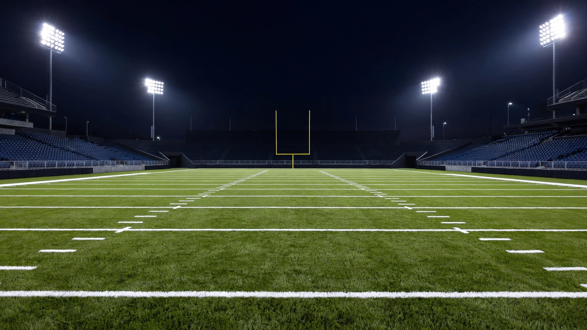 Empty American football field with goalposts under stadium lights at night