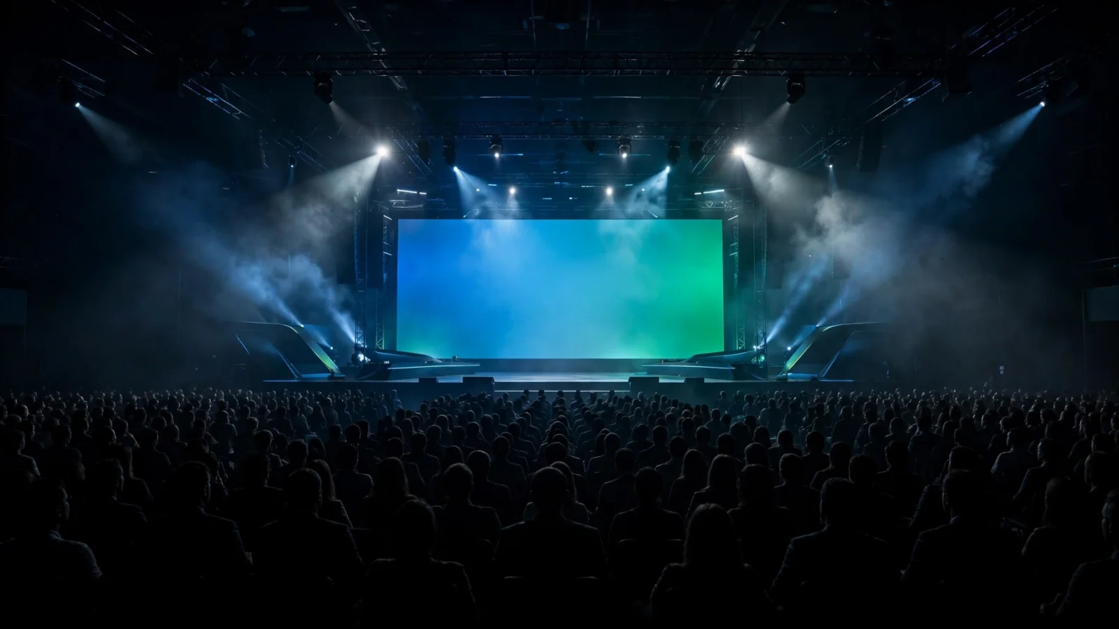 Thousands of attendees sit in a dark auditorium facing a large illuminated stage screen at a technology conference keynote