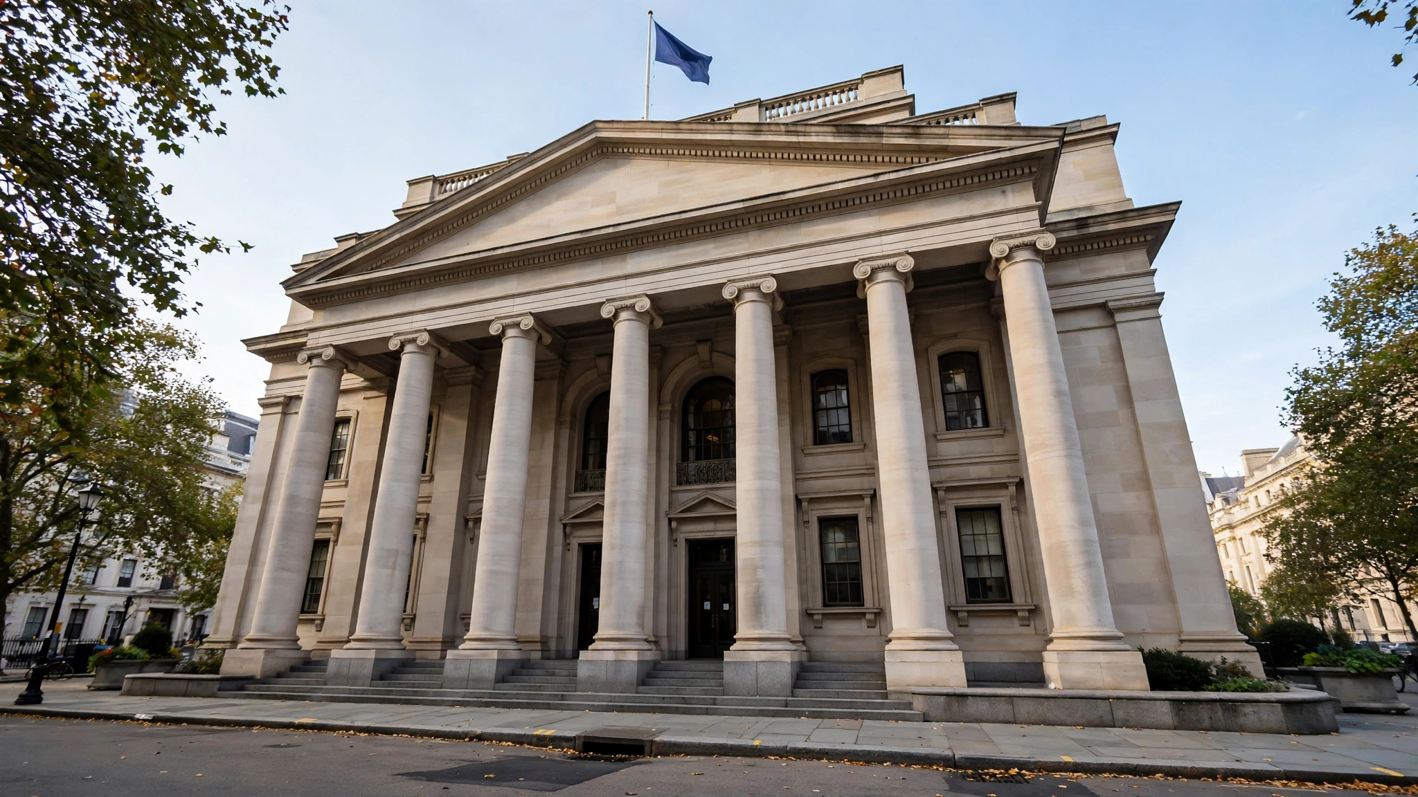 A neoclassical central bank building with tall columns and a flag on its roof, seen from the street