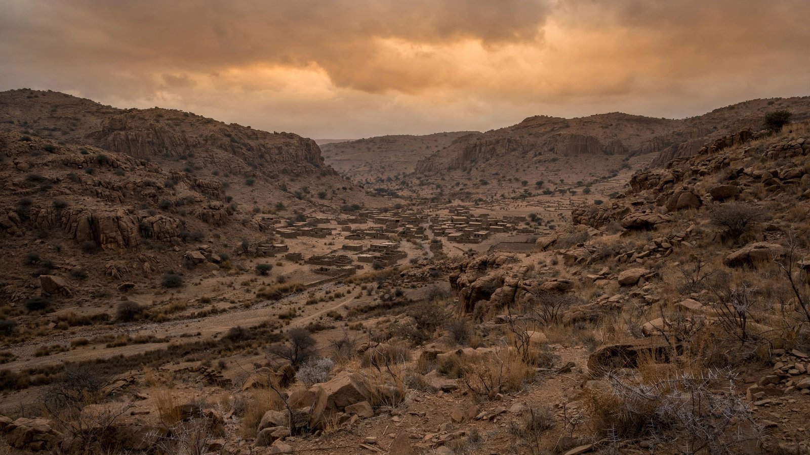 Arid rocky highlands and a small town in a valley in the Horn of Africa at dusk