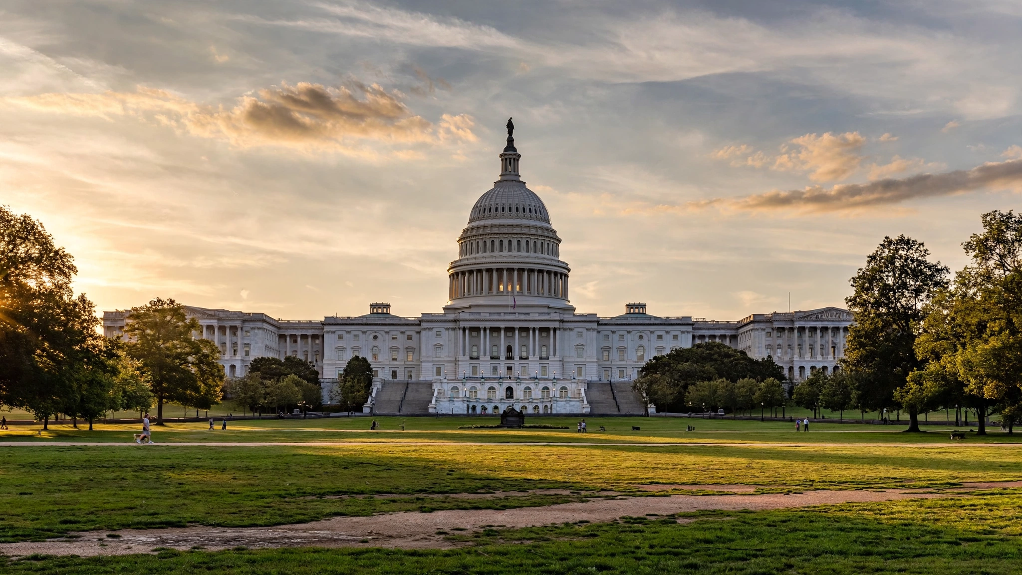 The United States Capitol building seen across a lawn at sunset
