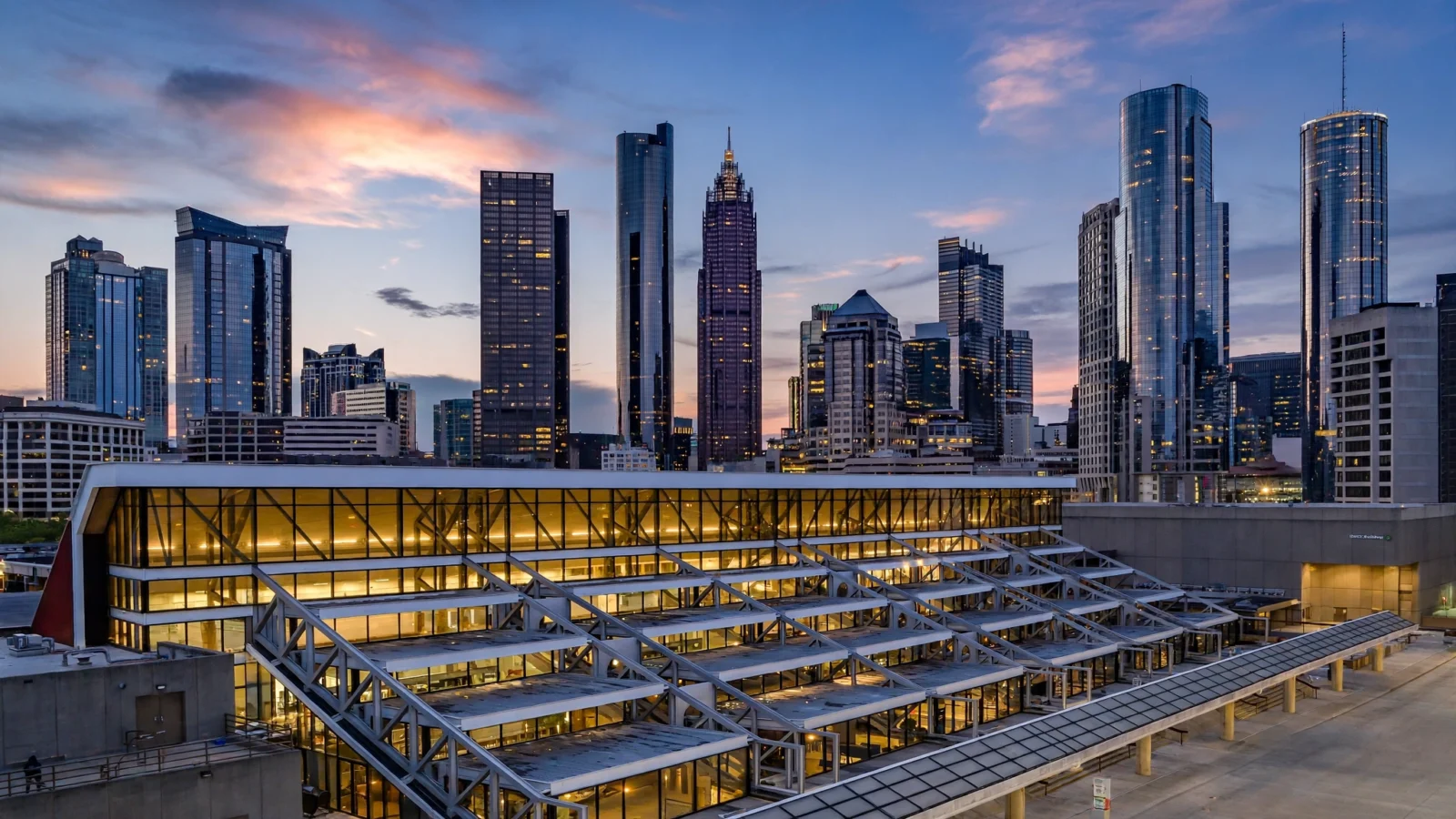 Downtown Atlanta skyline at dusk with a lit glass conference building in the foreground
