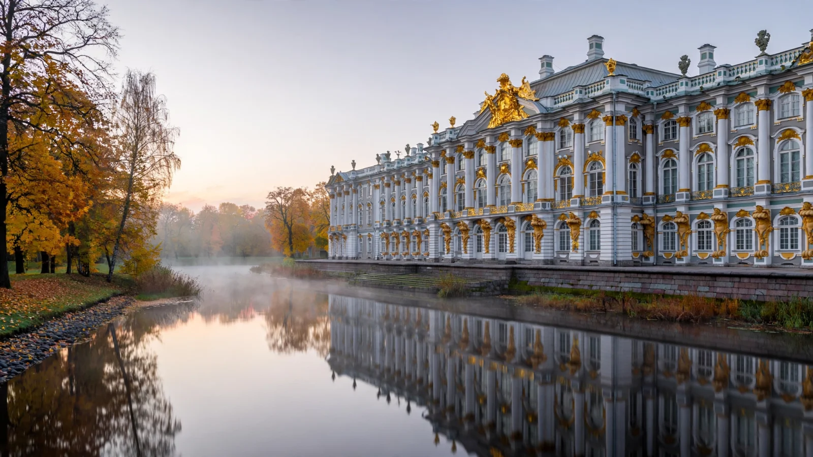 A grand imperial palace with gilded facades beside a calm river at dawn, autumn trees reflected in the water.