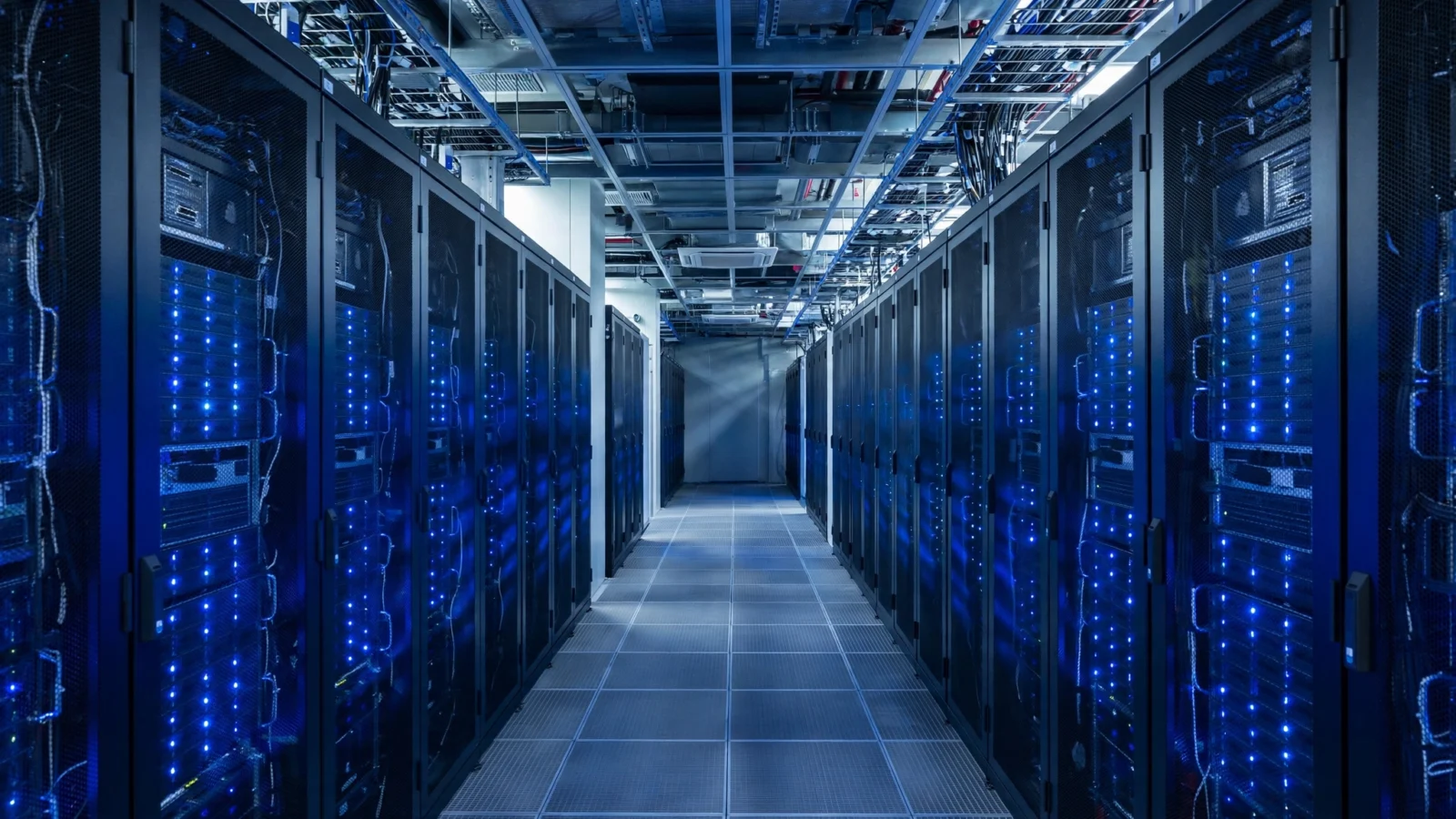 A corridor between rows of black server racks with blue indicator lights in a data center