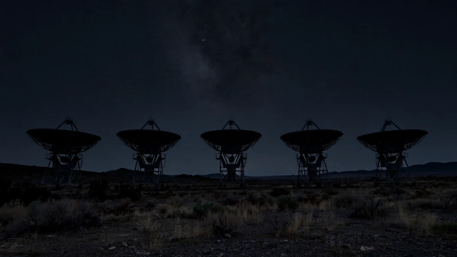 Satellite communications dishes silhouetted against a starry night sky
