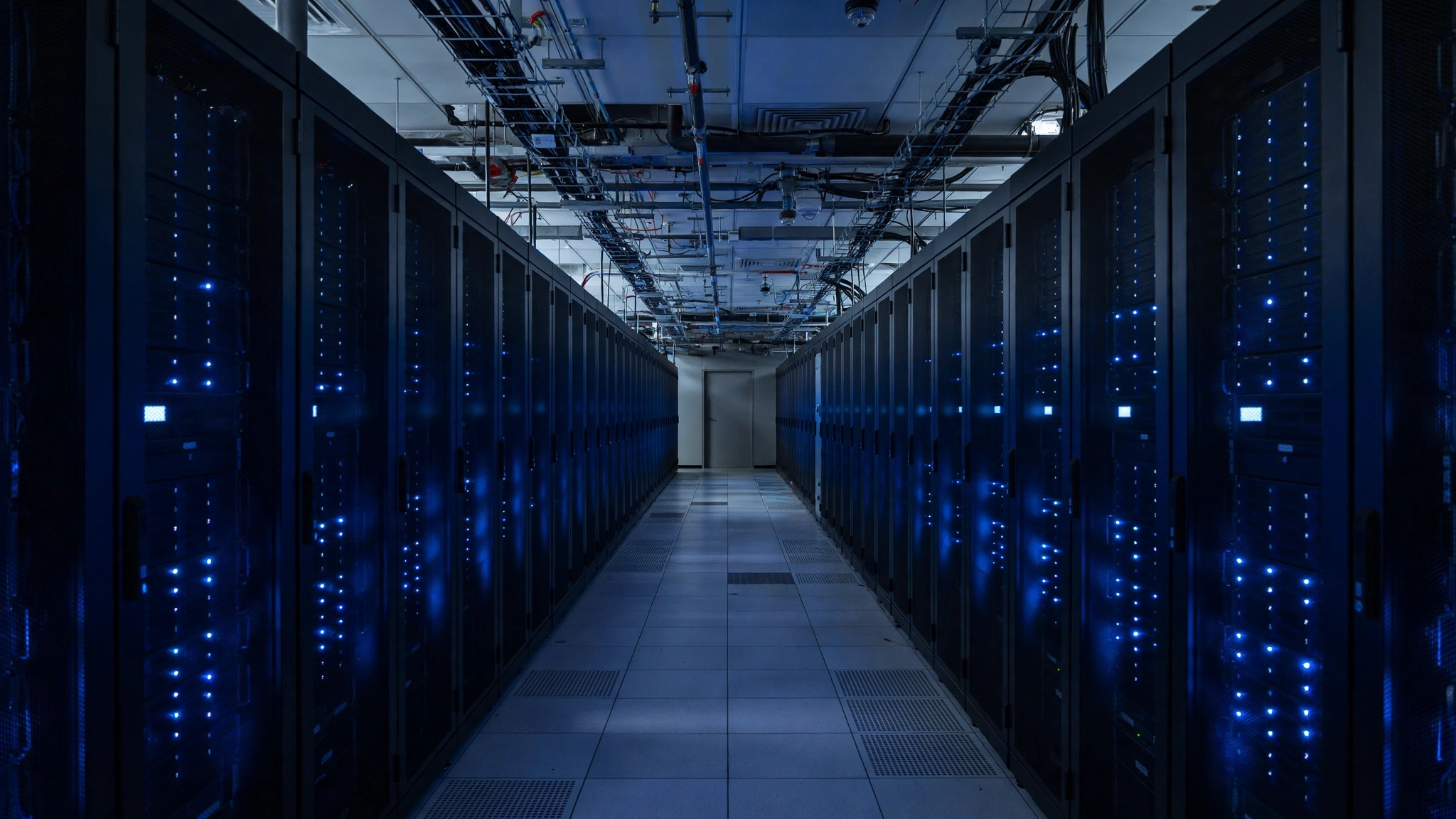 A corridor in a data center lined on both sides with server racks showing small blue lights.