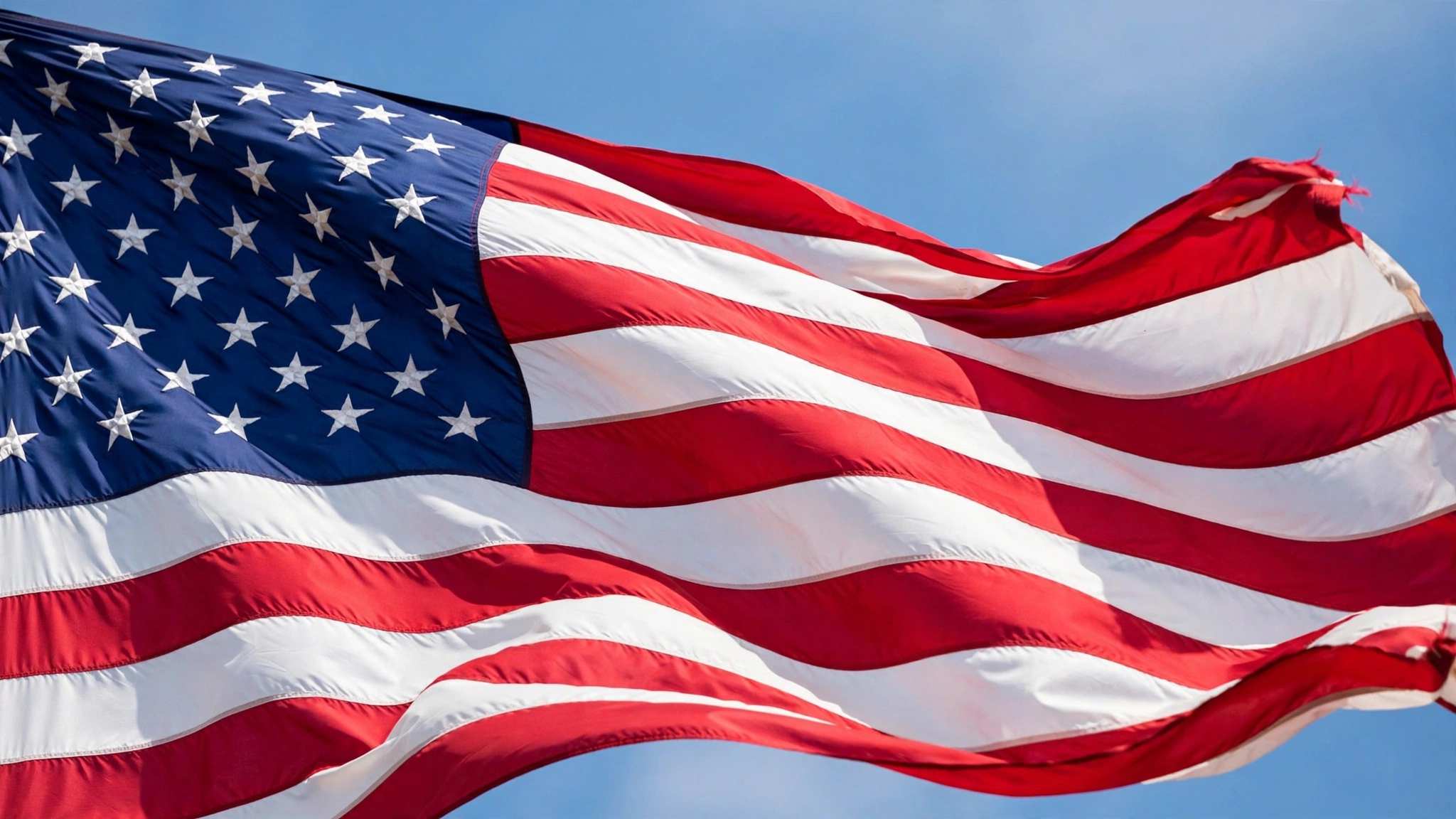 An American flag waving against a clear blue sky