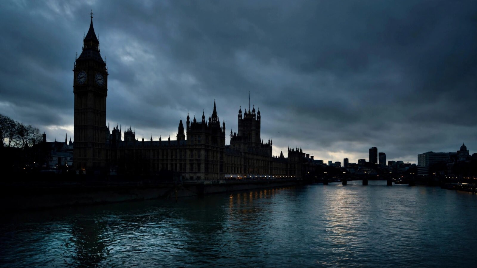 The Houses of Parliament and Big Ben silhouetted against dark clouds over the River Thames at dusk.