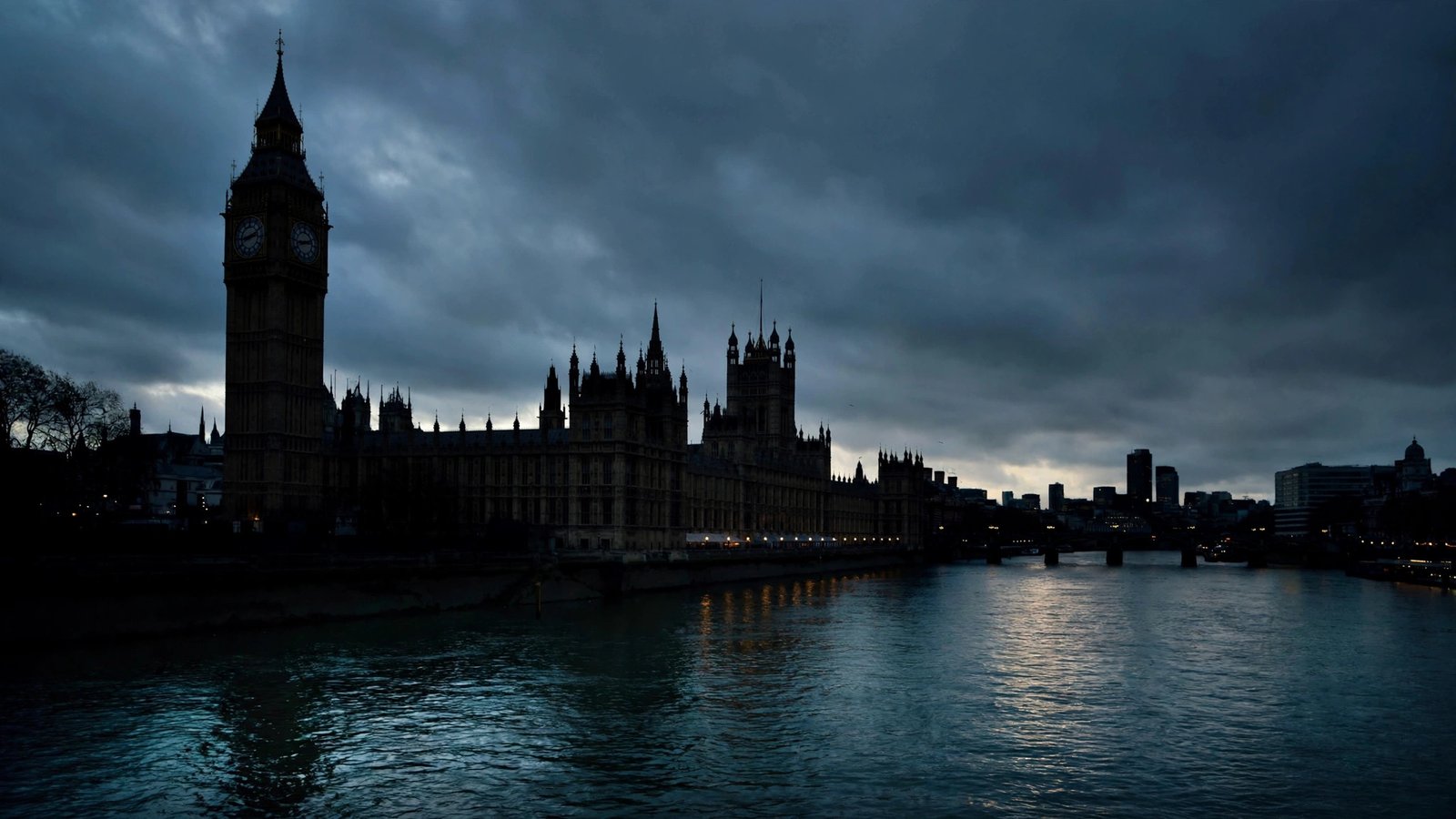 The Houses of Parliament and Big Ben silhouetted against dark clouds over the River Thames at dusk.